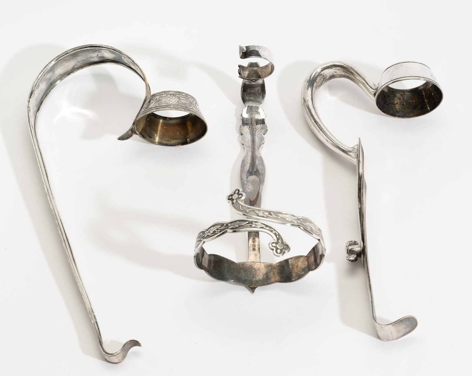 3 Antique English and American Silver Plate Wine Bottle Holders: DESCRIPTION: Includes an adjustable holder allowing for different sized bottles, stamped for International Silver Co.; and an early grip-fit piece marked Registered August 9, 1864 and additionally sta