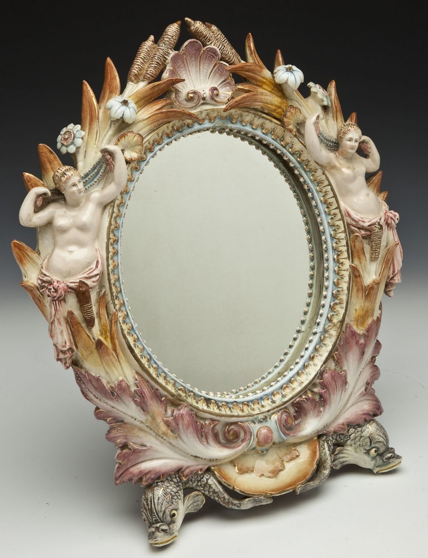 German Majolica Figural Table Mirror: DESCRIPTION: German majolica porcelain figural table mirror. Depicts two women and two fish among a floral and leaf motif with beading around the mirror's frame and with a metal stand verso. Marked "M