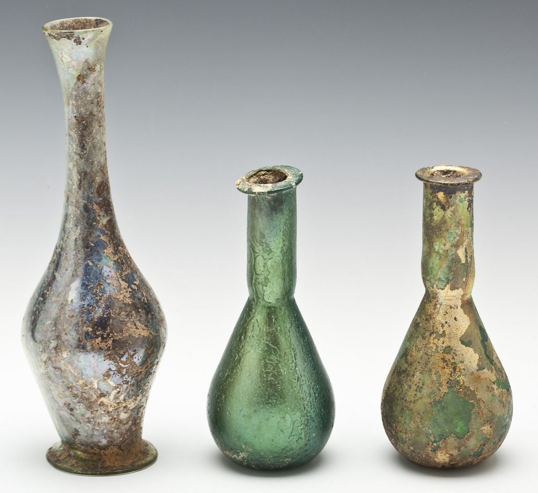 3 Ancient Roman Iridescent Glass Bottles: DESCRIPTION: A group of three ancient Roman iridescent glass bottles. Includes: 1) Thick green bottle with heavy gold iridescence. 6". 2) Thin clear with greenish tinge and blue iridescence. Touches o