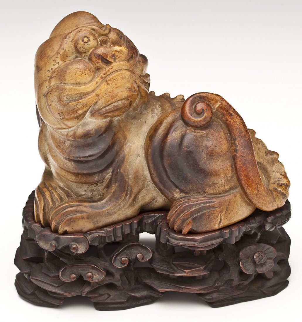 Ming Dynasty Soapstone Foo Dog: DESCRIPTION: A soapstone carving of a recumbent foo dog. Old label "Chinese dog foo Ming Dynasty soapstone." With fitted carved rosewood base. MEASUREMENTS: 6" x 3" x 4-1/2". Overall 6-1/2" with base.