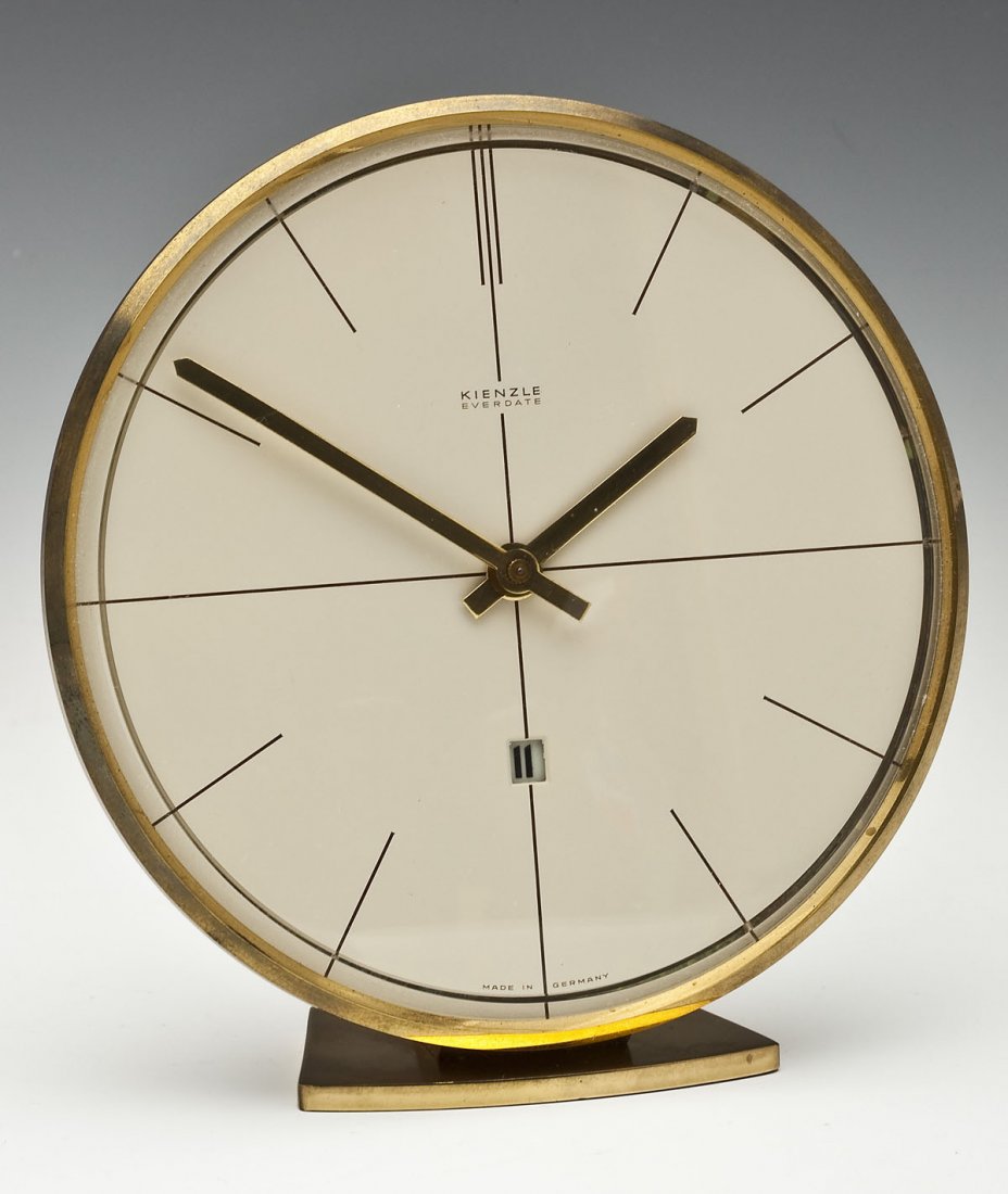 Mid-Century Kienzle Everdate Table Clock: DESCRIPTION: Kienzle Everdate table clock. Marked "Kienzle Everdate, Made in Germany," on the white dial with an area for the changing date. Also marked "Kienzle," verso. Circa 1950's. MEASUREMENTS: 6
