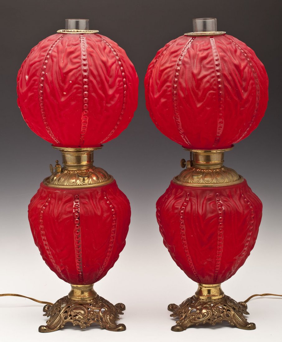 Pair of Cranberry Satin Gone with the Wind Lamps: DESCRIPTION: Pair of cranberry satin Gone with the Wind lamps. With a brass collar and reticulated base and with a sphere top and inverted tear drop shaped light-up base. Each marked "Made in U.S. of 