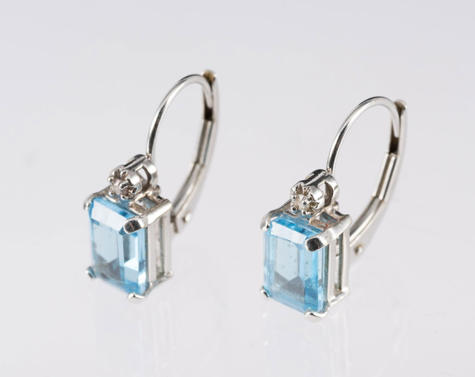 Mexican 14K Gold, Blue Topaz and Diamond Earrings: Spring-lock white gold earrings for pierced ears with emerald cut blue topaz gemstones with small diamond accents. Marked 14k Mexico and hallmarked. Weight 2.1 grams.