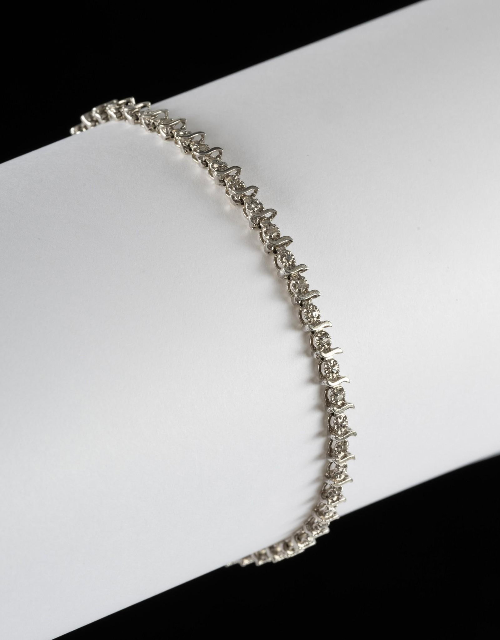 10K Gold and Diamond Tennis Bracelet: Marked 10k white gold tennis bracelet set with small diamonds. 7-1/4" long. 4.5 grams.