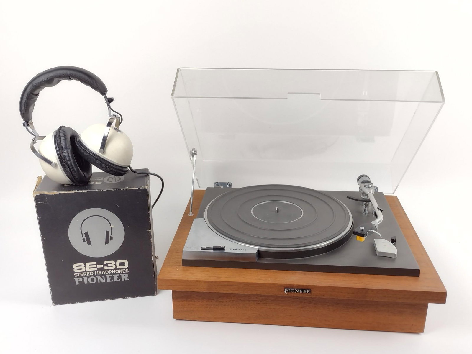 Pioneer Turntable and SE-30 Headphones: Powers on. Turntable number 30907. 20" wide x 16" deep x 7-1/2" high. Headphones model number SE-30. Black and white.