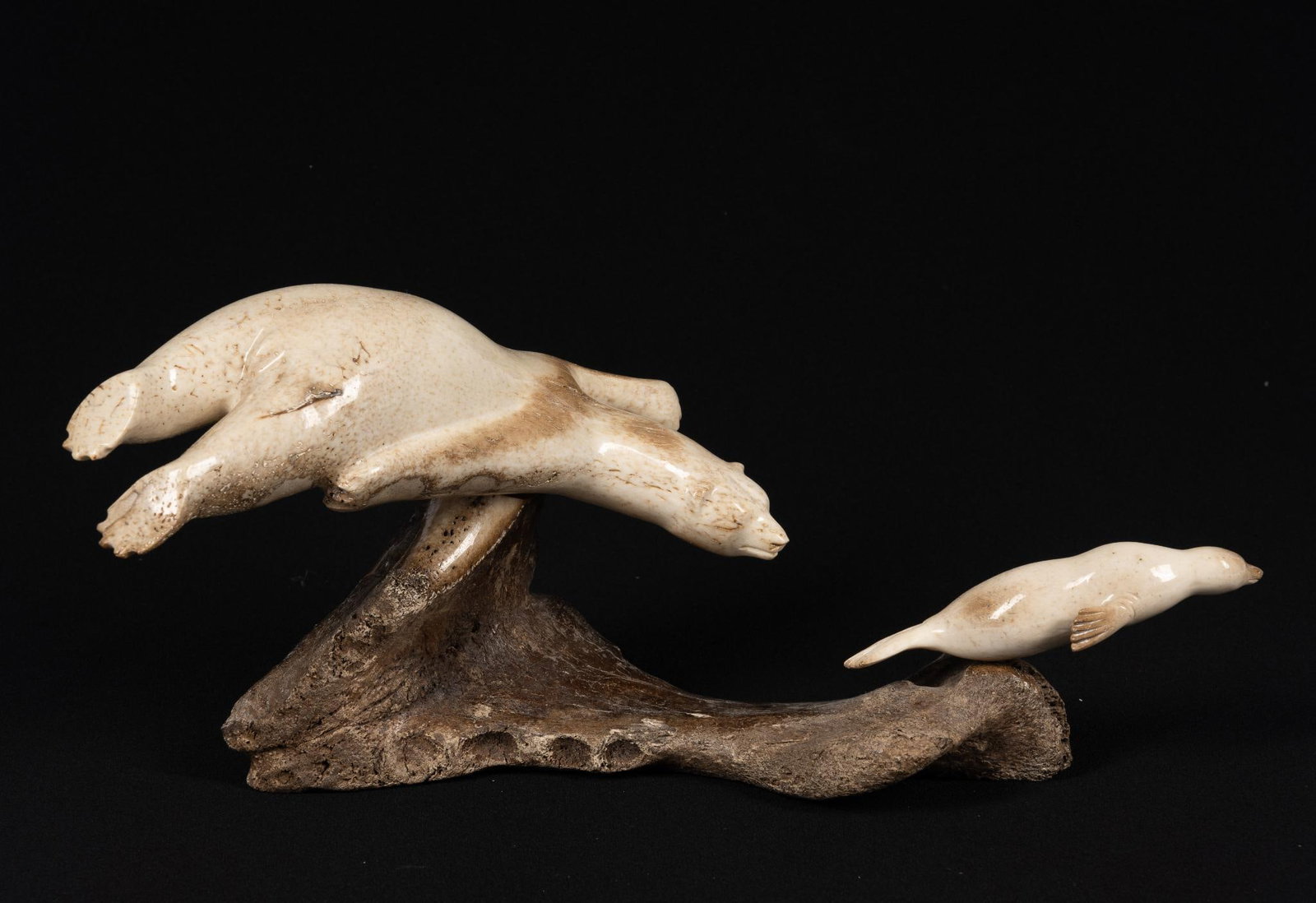 Carved Inuit Fossilized Bone by Chivly Chupak: NOT ELIGIBLE FOR IN-HOUSE SHIPPING. Underwater scene of polar bear chasing a seal in carved fossilized bone. Length 12" Chivley Chupak, Juneau, AK.