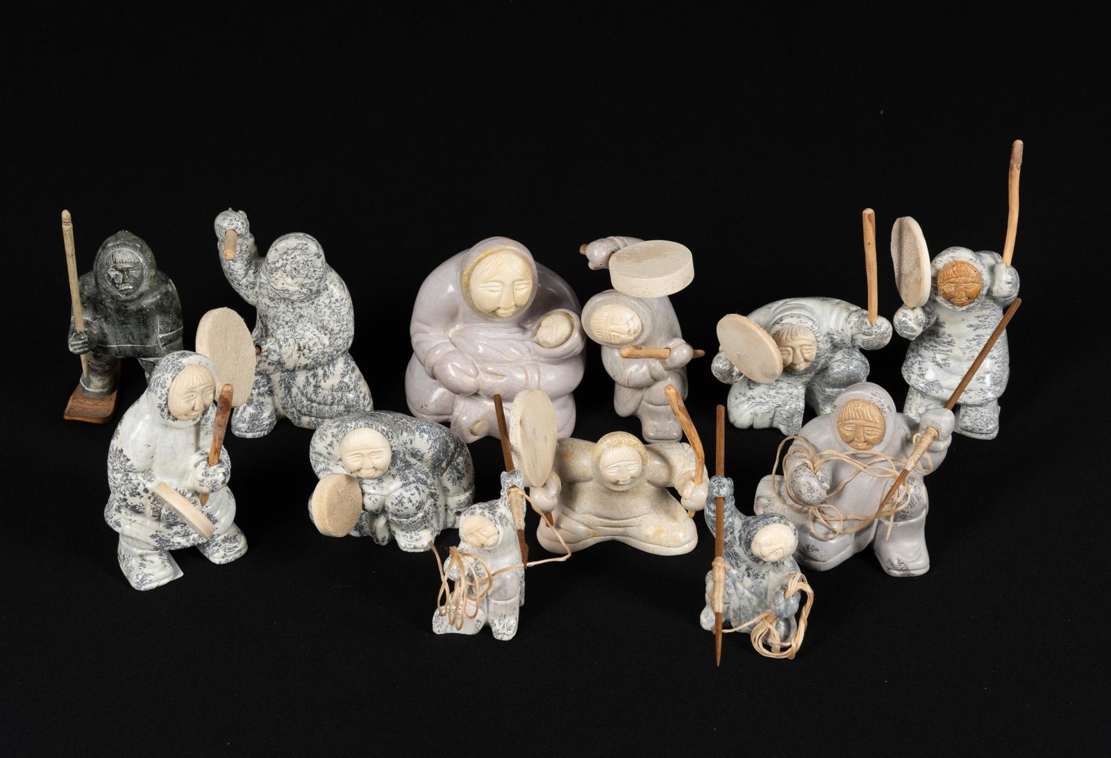 12 Carved Inuit Stone Figures: NOT ELIGIBLE FOR IN-HOUSE SHIPPING. Figures are 3" to 4-1/2" height not including attachments. One figure is missing the carved bone face and some of the implements may be missing. Overall good condit