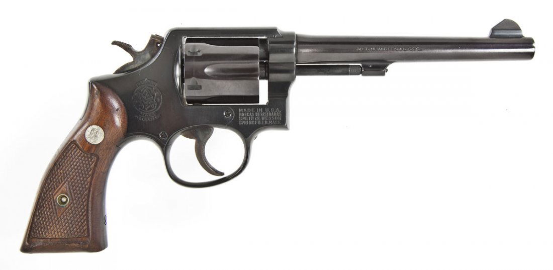 Smith & Wesson Model 10 Revolver - .38 Spl.: SERIAL #: 440631 DESIGN: Double action with swing out 6-shot cylinder. 6” barrel. MATERIAL/FINISH COMPOSITION: Blued steel. Checkered wood grip panels. FEATURES: Blade front sight. Rear sight is gro