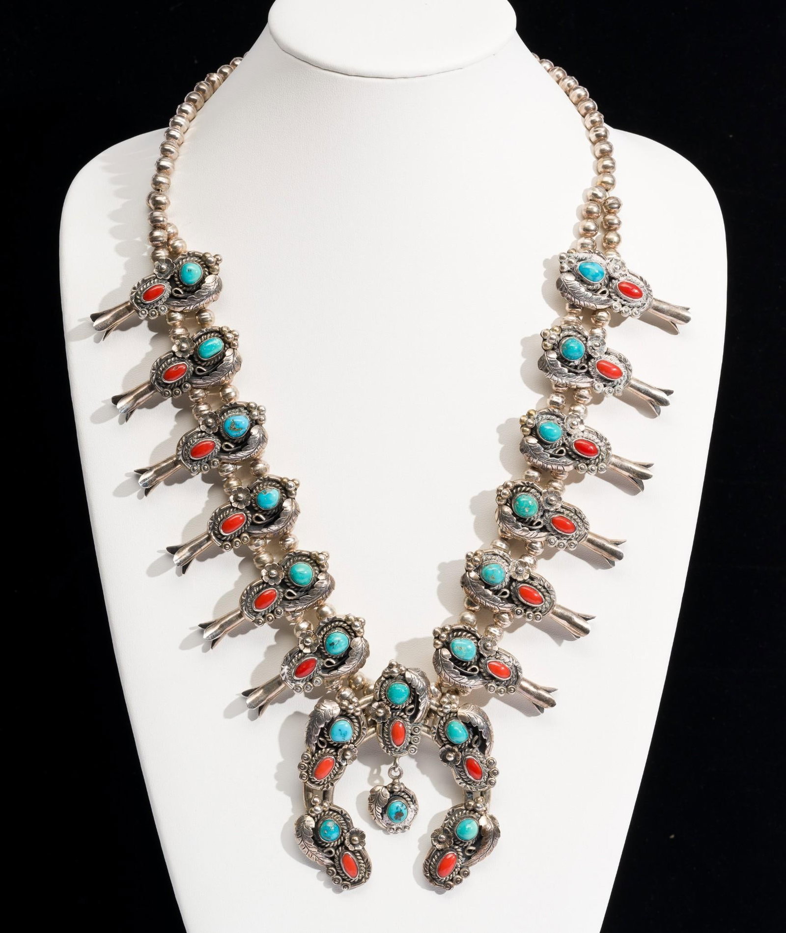 Navajo Sterling Silver And Turquoise Squash Blossom Necklace: DESCRIPTION: A substantial silver squash blossom necklace with turquoise and coral hallmarked RBP Raymond Platero, approximately late 1970's. MEASUREMENT: 26" length with 3" pendant. Total weight of 8