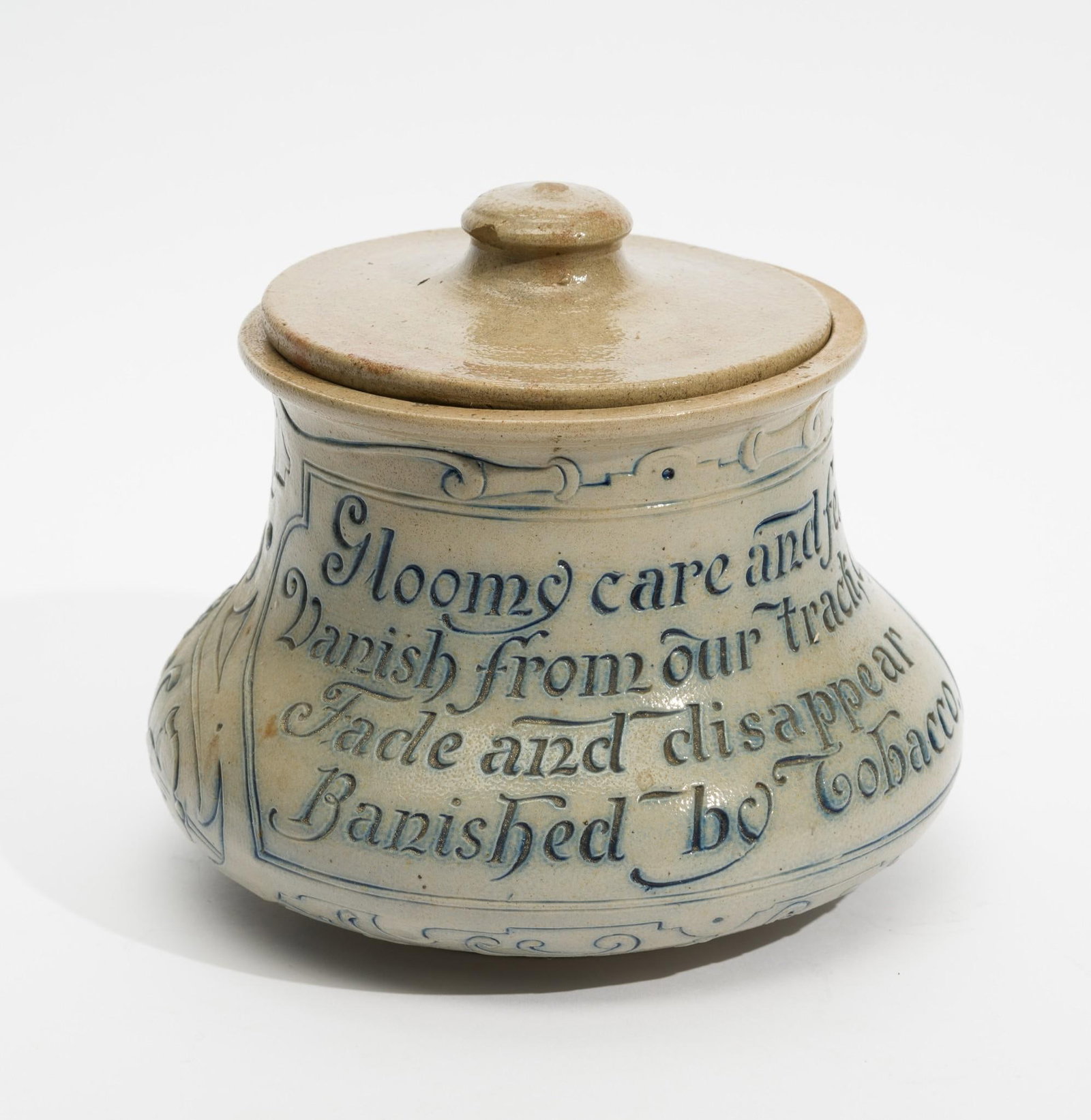 Ges. Gesch German Stoneware Tobacco Jar: "Gloomy care and fear vanish from our track, oh! Fade and disappear Banished by Tobacco". 6-1/4" diameter x 5-1/2" high. Loss to lid. Loss to top rim of jar and rack on right side up to top rim. Lid i