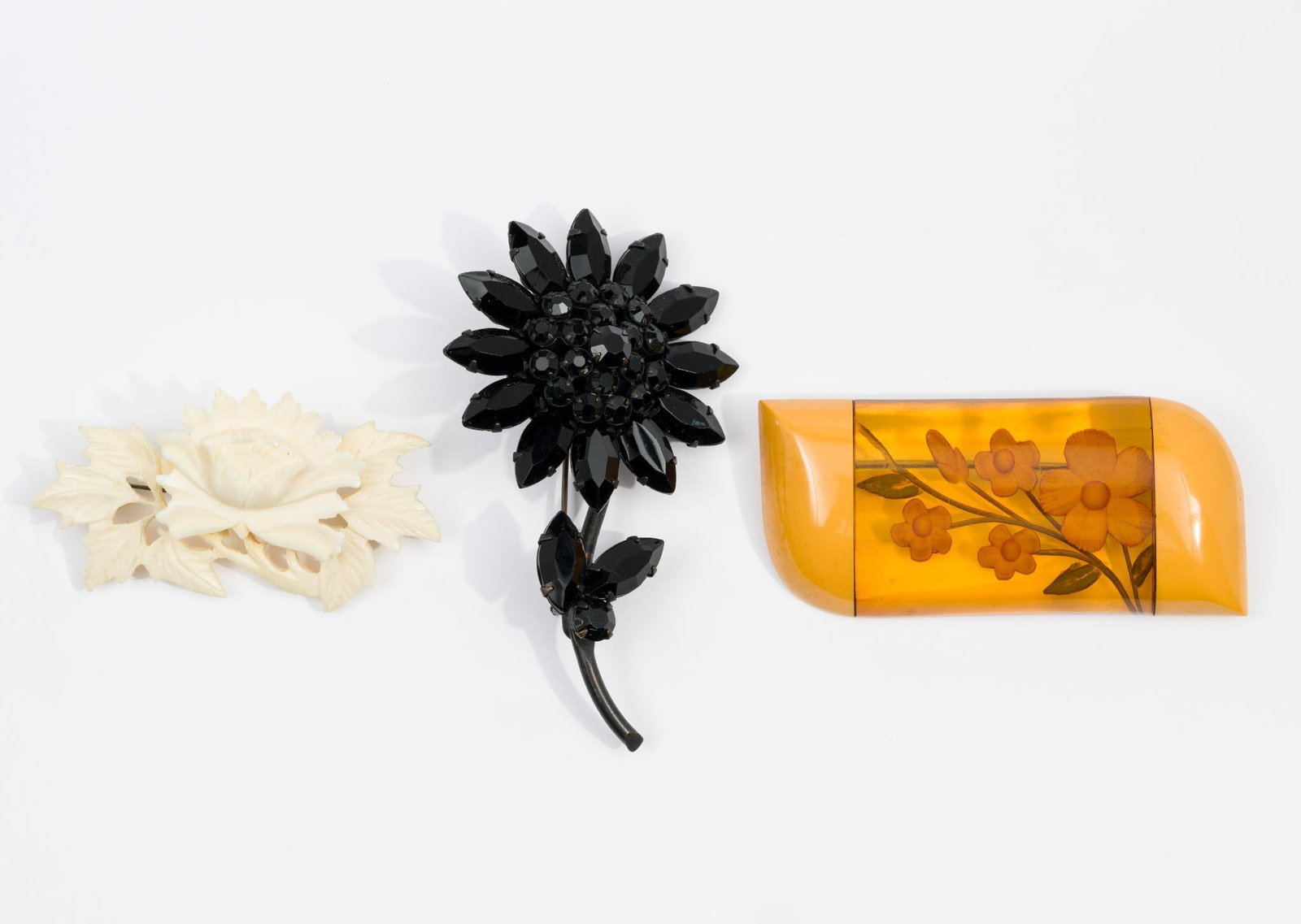 3 Vintage Flower Brooches: Includes bakelite and lucite, carved bone, and black rhinestone. 1-1/4" to 3-1/8" high.