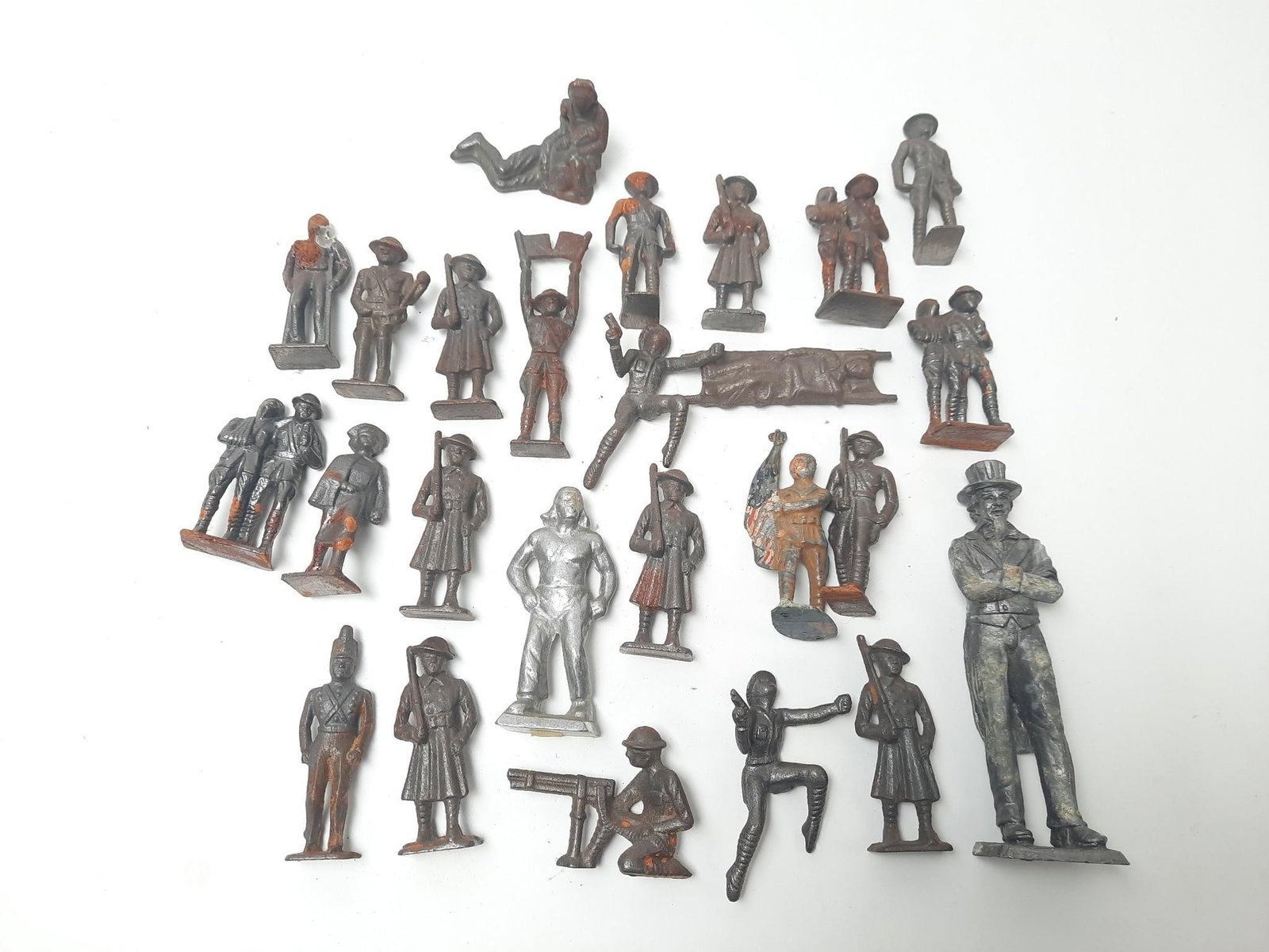 25 Metal Figurines: Mostly soldiers. 2" to 6-1/4" high. Wear and rust.