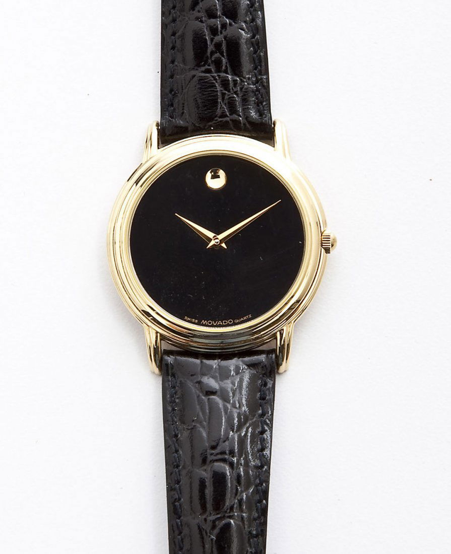 Movado Museum Wristwatch NIB: DESCRIPTION: Movado The Museum wristwatch. Black face with single goldtone numeral marker at 12, marked "Swiss Movado Quartz". Goldtone bezel and stainless steel back. Back cover marked "Movado Stainl