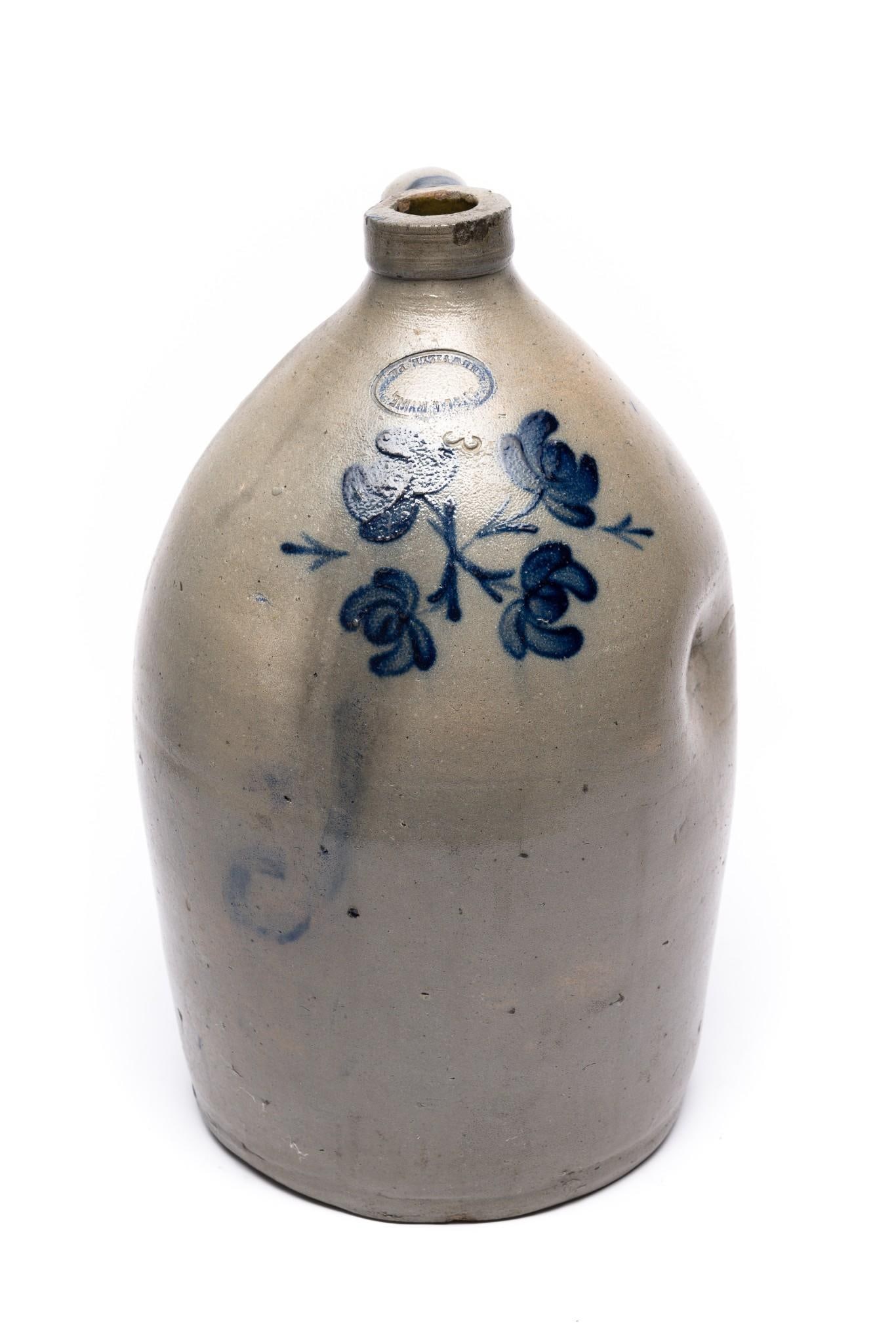 Samuel Irvine, Newville, PA 3 Gallon Floral Stoneware Crock: Stamped mark. Circa 19th century. Floral cobalt motif design. Dimple to left side. Cobalt highlights to handle. 16-1/2" tall.