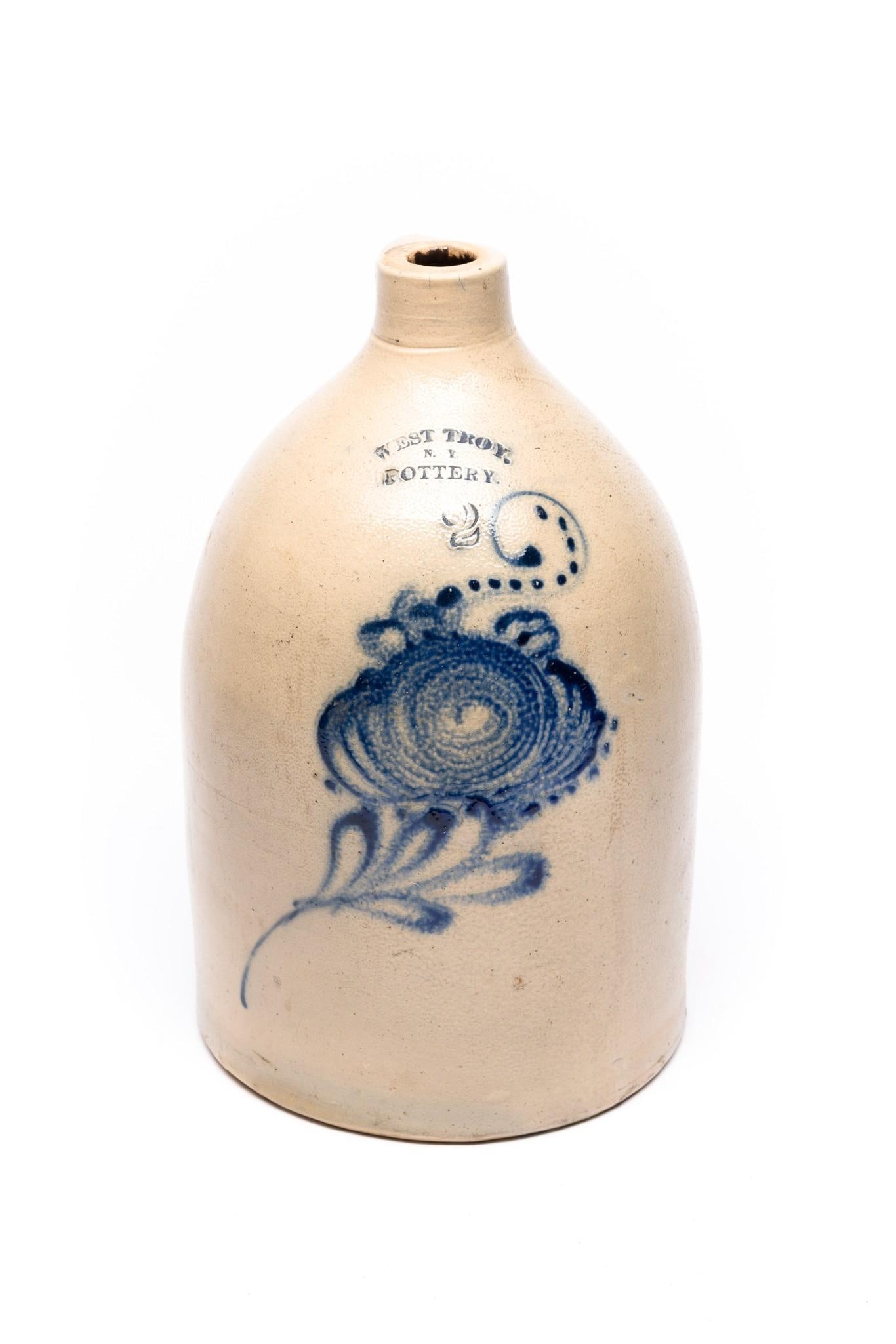 West Troy Pottery NY 2 Gallon Floral Cobalt Stoneware Jug: Circa 19th century. Floral cobalt motif. 14" tall. Crack in handle.