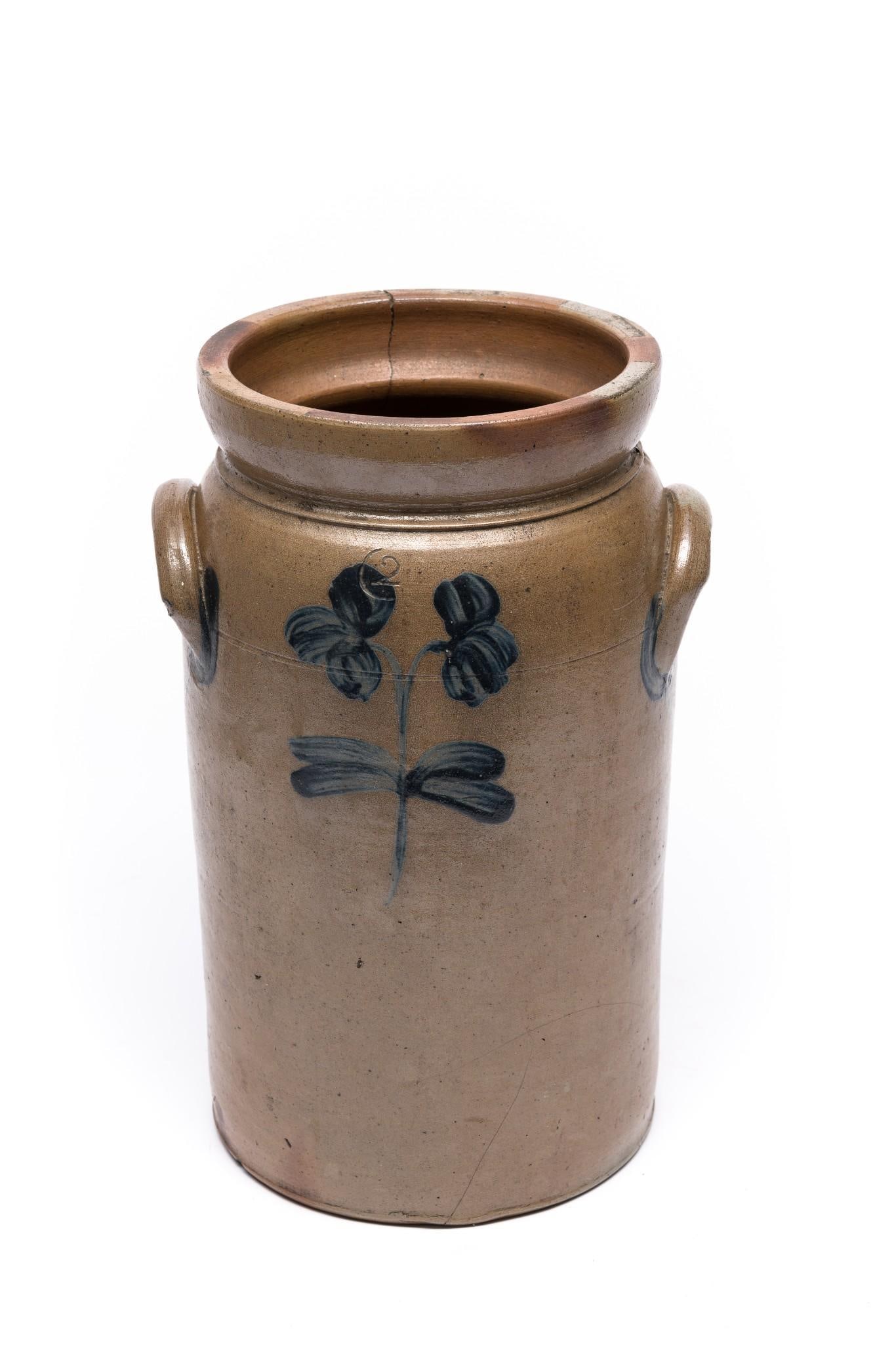 2 Gallon Cobalt Floral Stoneware Jug: Cobalt blue floral motifs on front and back with cobalt highlights on handles. Stamped mark. Crack down 1/4 of the way on one side, but overall good. 14-1/2" tall.