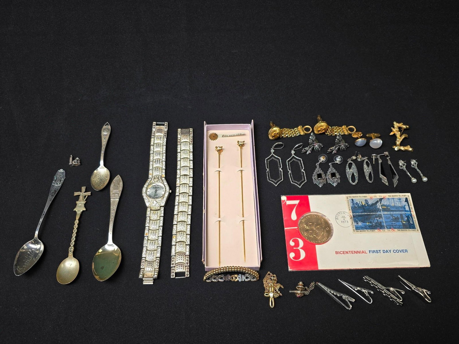 34 Pieces of Costume Jewelry Incl Sterling: Includes four sterling marked souvenir spoons, six pairs of sterling marked earrings, and several costume jewelry pieces. Also includes Charles Raymond fashion watch and bracelet. Watches 9-1/4" long.