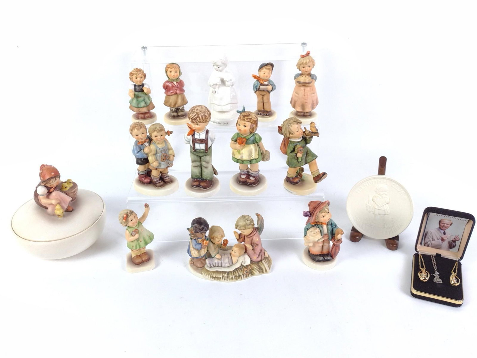 17 Hummel Figurines and Collectibles: Includes 3 necklaces, 1 plaque, 1 covered dish, and 12 figurines. 4" to 6" high.