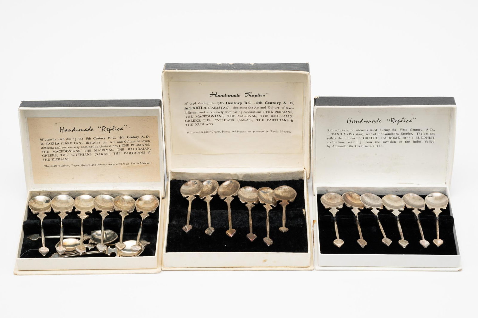 21 Silverplate Spoons: Hand-made "Replica" of utensils used during the 5th century B.C. - 5th Century A.D. in Taxila Pakistan. Spoons each: 3-1/2" long. One box with 3 additional spoons. Boxes with some finish losses and te