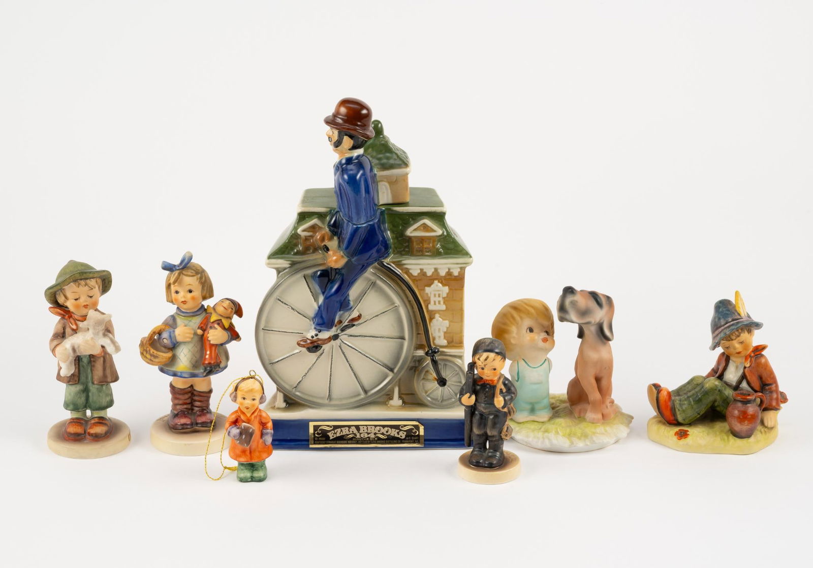 6 Figurines and Decanter Bottle incl Hummel and Goeble: 3" to 10-1/2" high. Decanter is empty. Chimney Sweep figurine with repaired ladder.