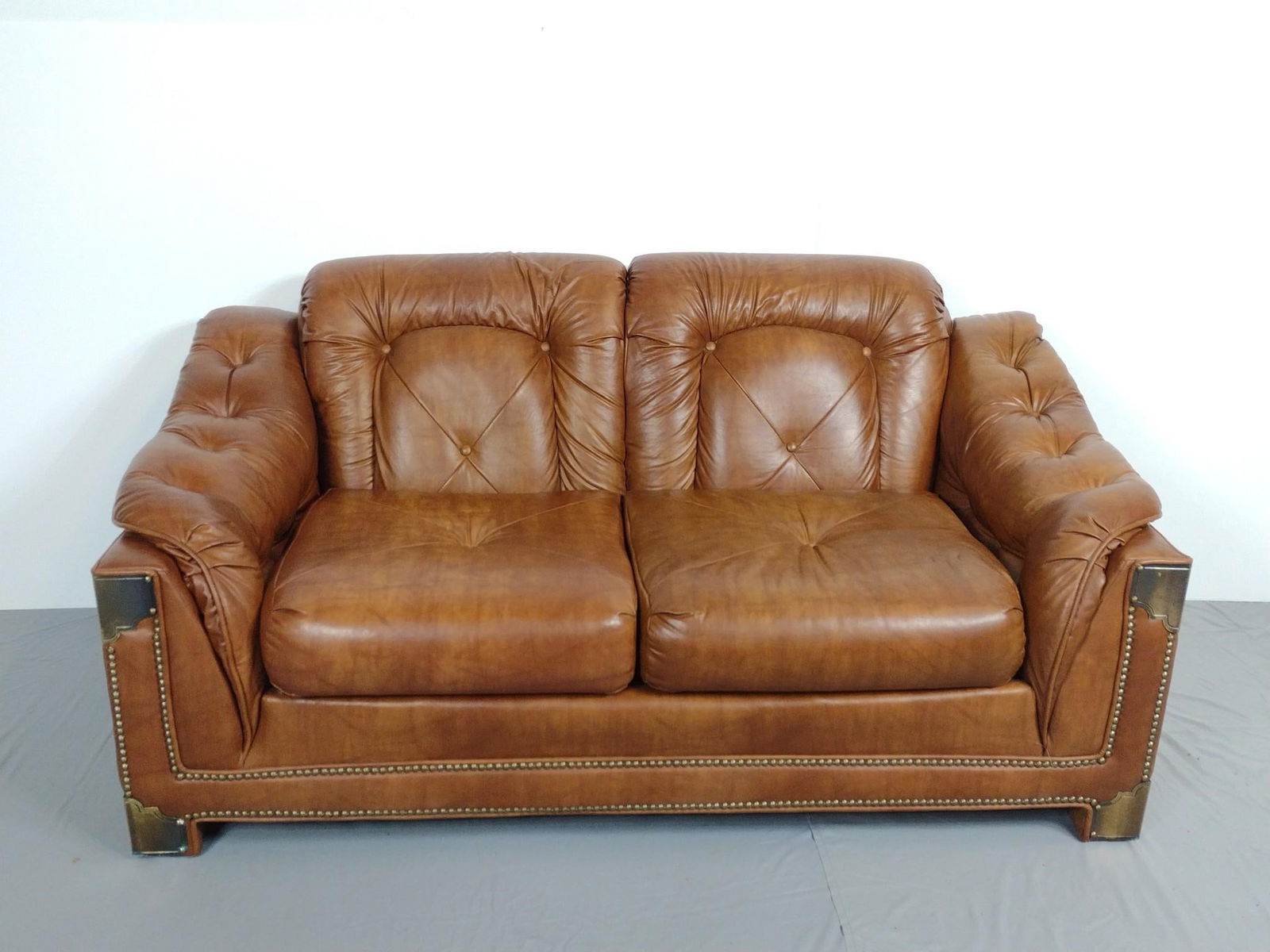 Sears Synthetic Leather Loveseat With Brass Accents: NOT ELIGIBLE FOR IN-HOUSE SHIPPING. 64" wide X 36" deep X 32" high.