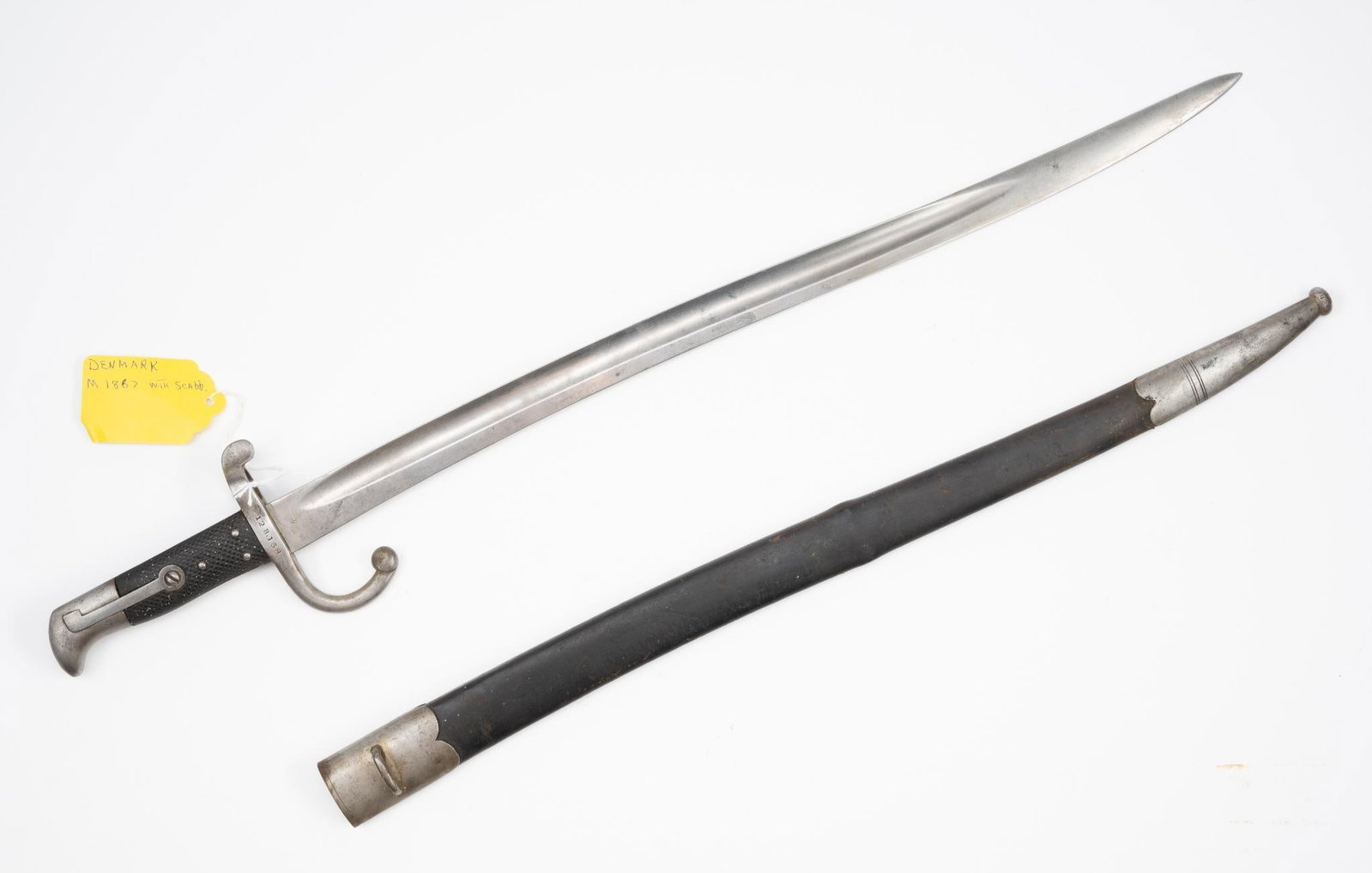 Denmark M1867 Bayonet: NOT ELIGIBLE FOR IN-HOUSE SHIPPING OUTSIDE THE UNITED STATES. With scabbard. Blade marked W. Holler Solingen. Hilt marked 2933 & 12 B.168. 27-3/8" long.