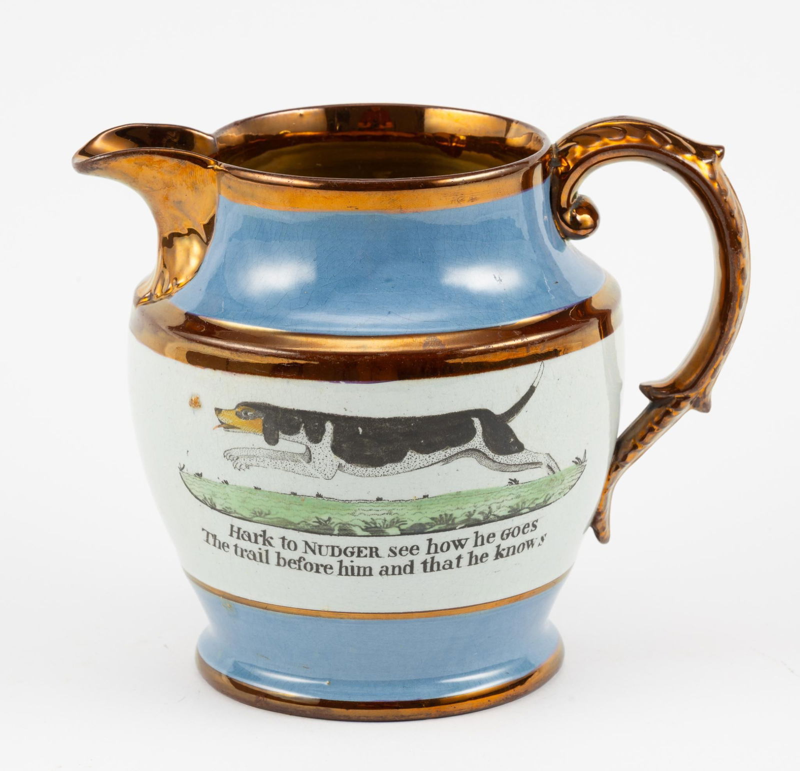 Rare Old Nudger Hunting Dog Lustreware: Provenance: Single owner collection. Depicts elongated hunting dog with the title "Old Nudger." Medium blue and white banded with copper lustre. Picture of hunting dog with poem about the Saddleworth