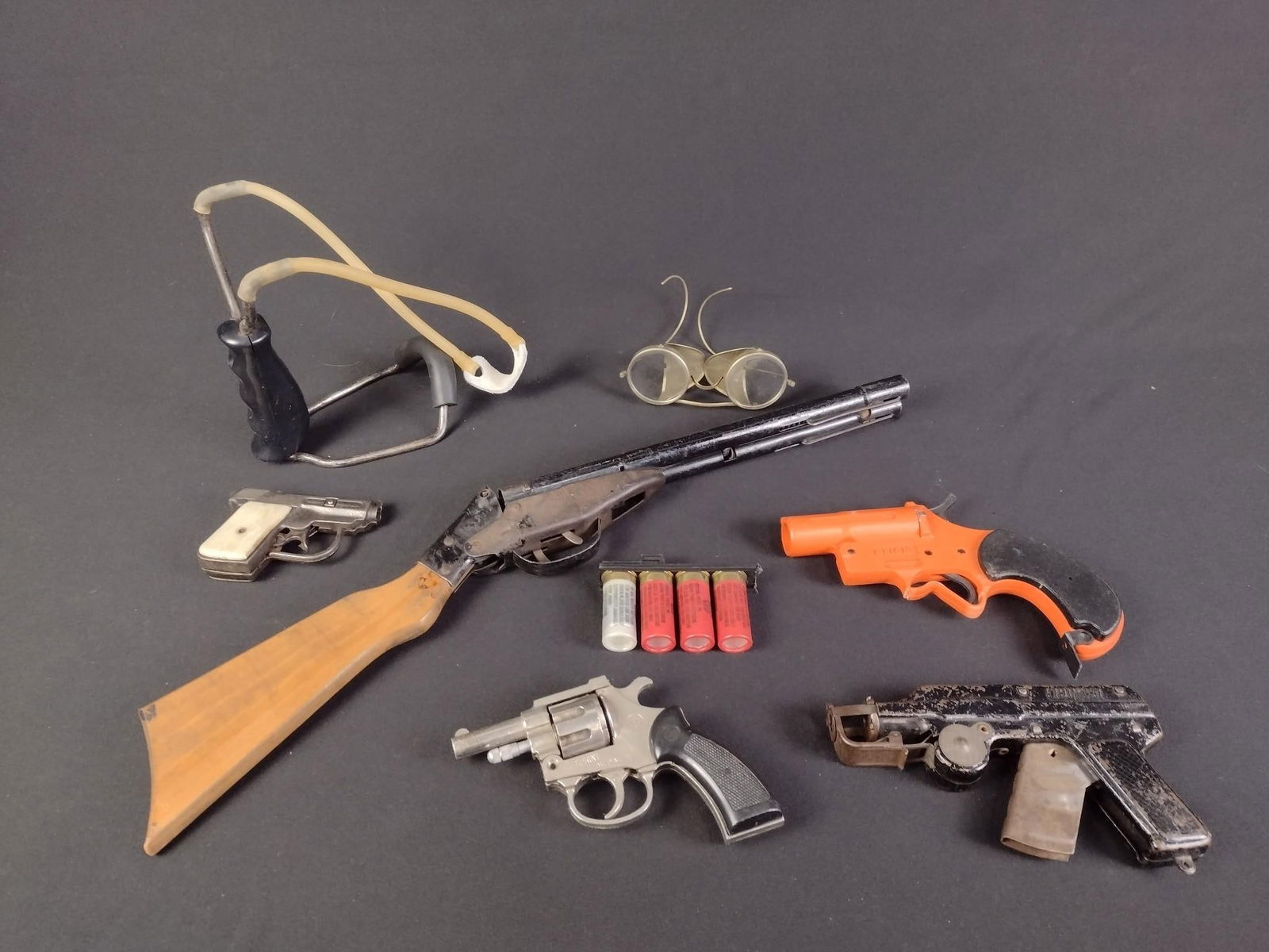 8 Pcs Toy Guns & Accessories: NOT ELIGIBLE FOR IN-HOUSE SHIPPING. Includes toy guns, slingshot, and more.