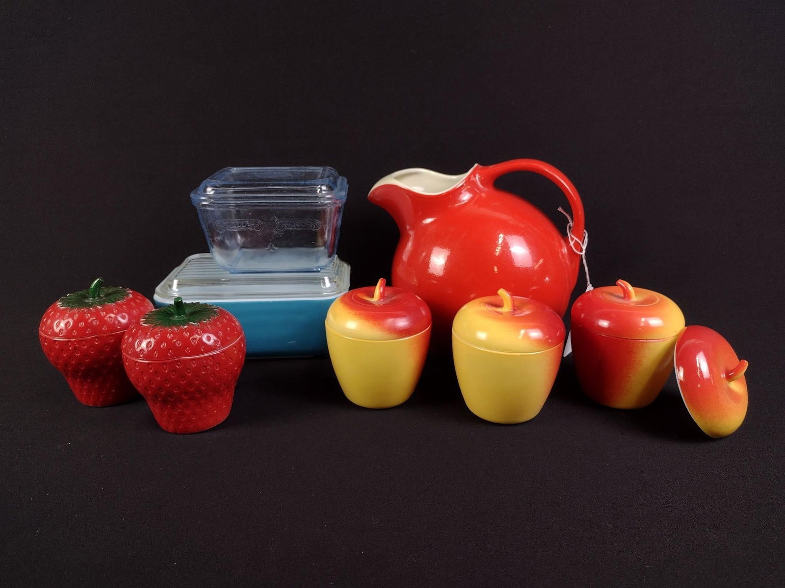 9 Pcs Vintage Kitchenwares incl Fruit Form Refrigerator Jars: Includes red Hall pitcher, 5 fruit form jars, 1 fruit lid without base, blue Pyrex refrigerator dish and blue tinted Fire King refrigerator dish. 1-1/2" to 7" high.