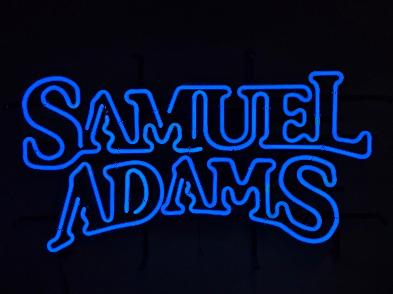 Samuel Adams Neon Sign: NOT ELIGIBLE FOR IN-HOUSE SHIPPING. Working. Overall: 26" wide x 5-1/2" deep x 15-1/2" high. PROVENANCE: From the Collection of Robert L. Hassenplug—a proud veteran and small business owner was an a