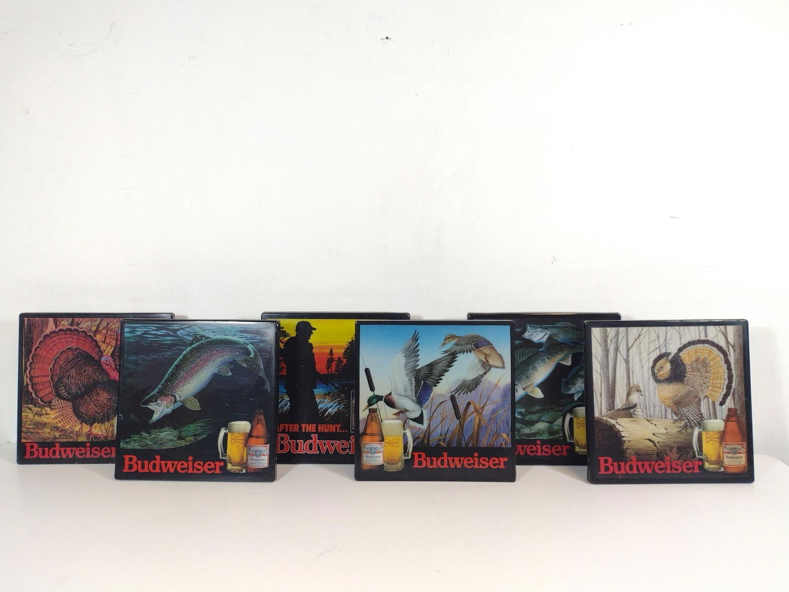 6 Budweiser Signs: NOT ELIGIBLE FOR IN-HOUSE SHIPPING. Each 18" wide X 18" high. PROVENANCE: From the Collection of Robert L. Hassenplug—a proud veteran and small business owner was an avid and passionate collector of