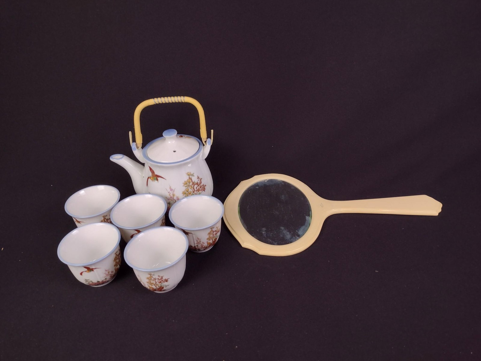 Small Tea Set and Pyralin Mirror: Includes tea pot, five matching tea cups, and a Pyralin DuBarry mirror. The mirror overall: 8" wide x 14" high. Some haziness and spots with the mirror from age.