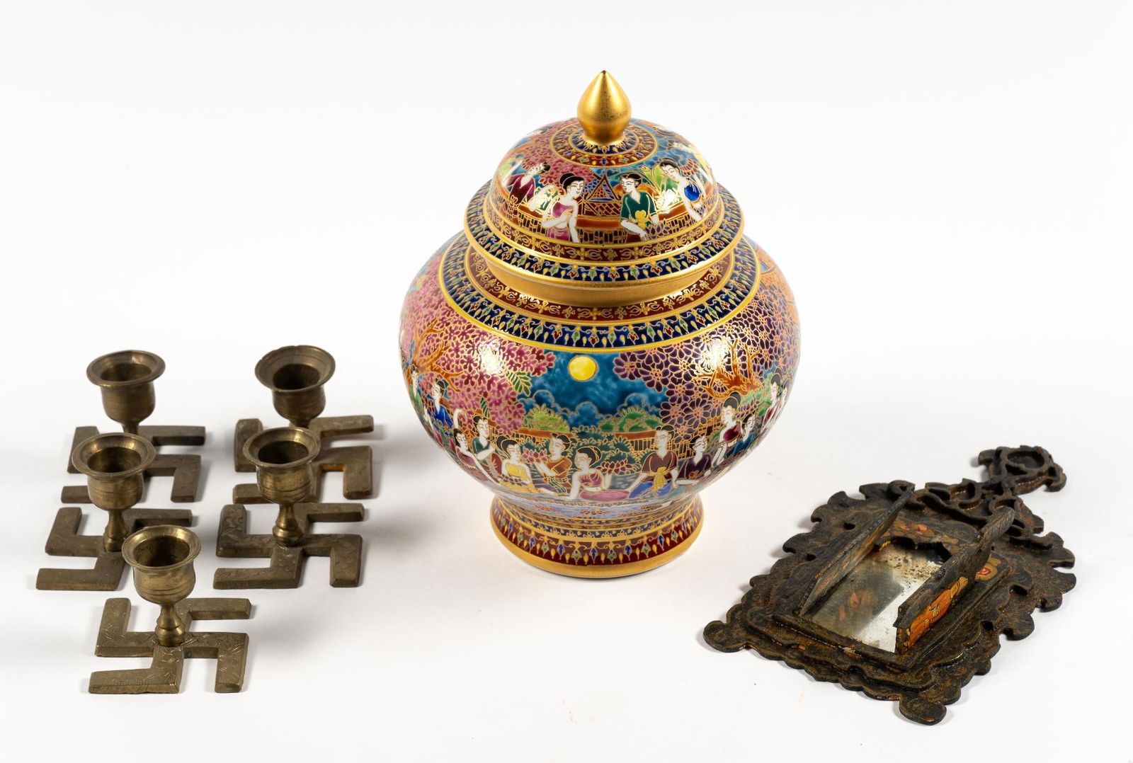 (7) South Asian Curios: Includes set of (5) Hindu swastika candlesticks with floral motifs representing good fortune; a Thai Benjarong modern urn; and a Antique hand mirror with hand painted decoration. All in very good cond