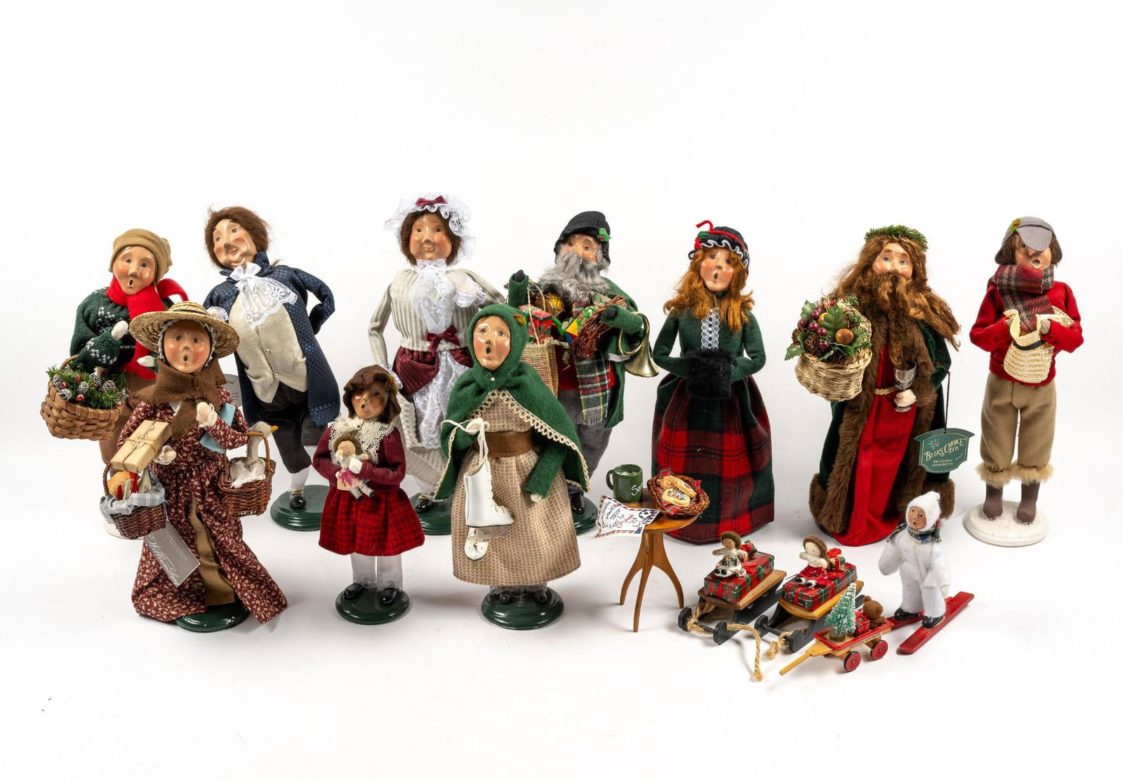 15 Byers' Choice Carolers and Accessories: NOT ELIGIBLE FOR IN-HOUSE SHIPPING - See Terms for Shipping Options. Includes 11 Carolers and 4 accessories, such as a cookies and milk table, 2 sleds, and Toyland Express cart. From 3-1/2" to 14" tal