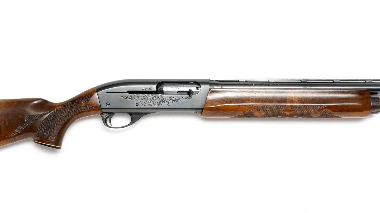 Remington Model 1100 12 Gauge Shotgun: A Remington Model 1100 semi automatic shotgun chambered in 12 gauge with 2.75" chamber. Shotgun has 27 3/4" barrel with choke (M) installed and ventilated rib. Engraved receiver and walnut stock and f