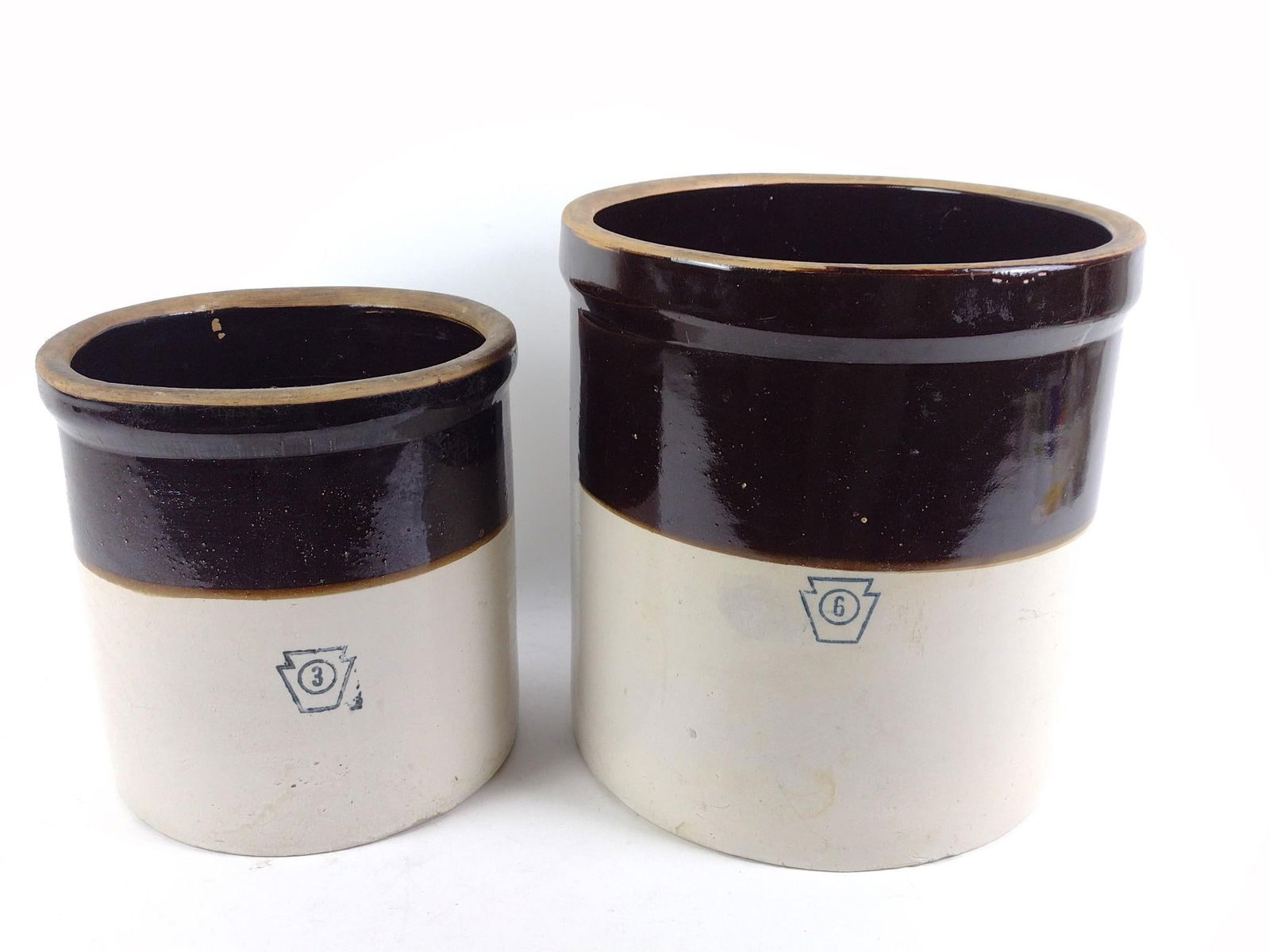 2 Stoneware Crocks: 6 gallon and 3 gallon. 11" to 13" wide x 11" to 13-3/4" high.