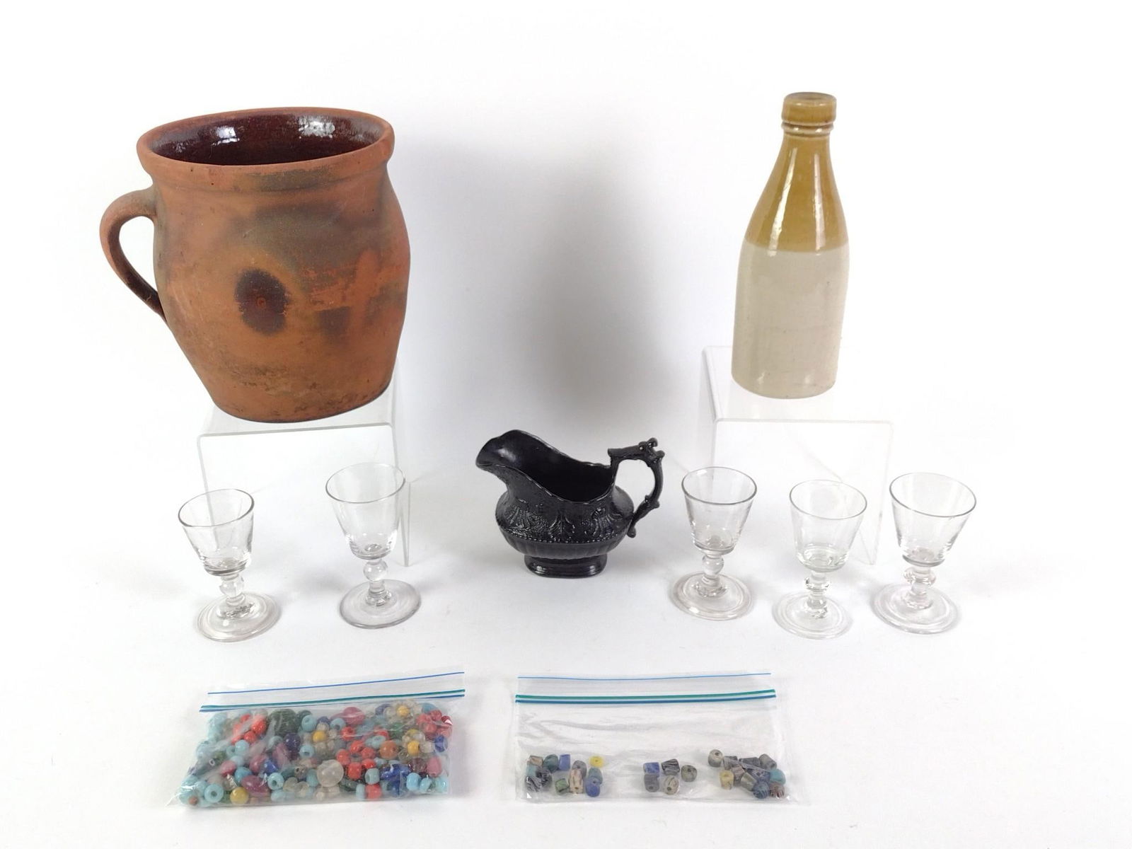 Antique and Vintage Ceramic and Glass: Includes redware pot, a vintage ginger beer bottle marked Grosvenor Glasgow, five small glasses, a black ceramic creamer jar, and vintage glass beads. From 4" to 7-1/2" tall.