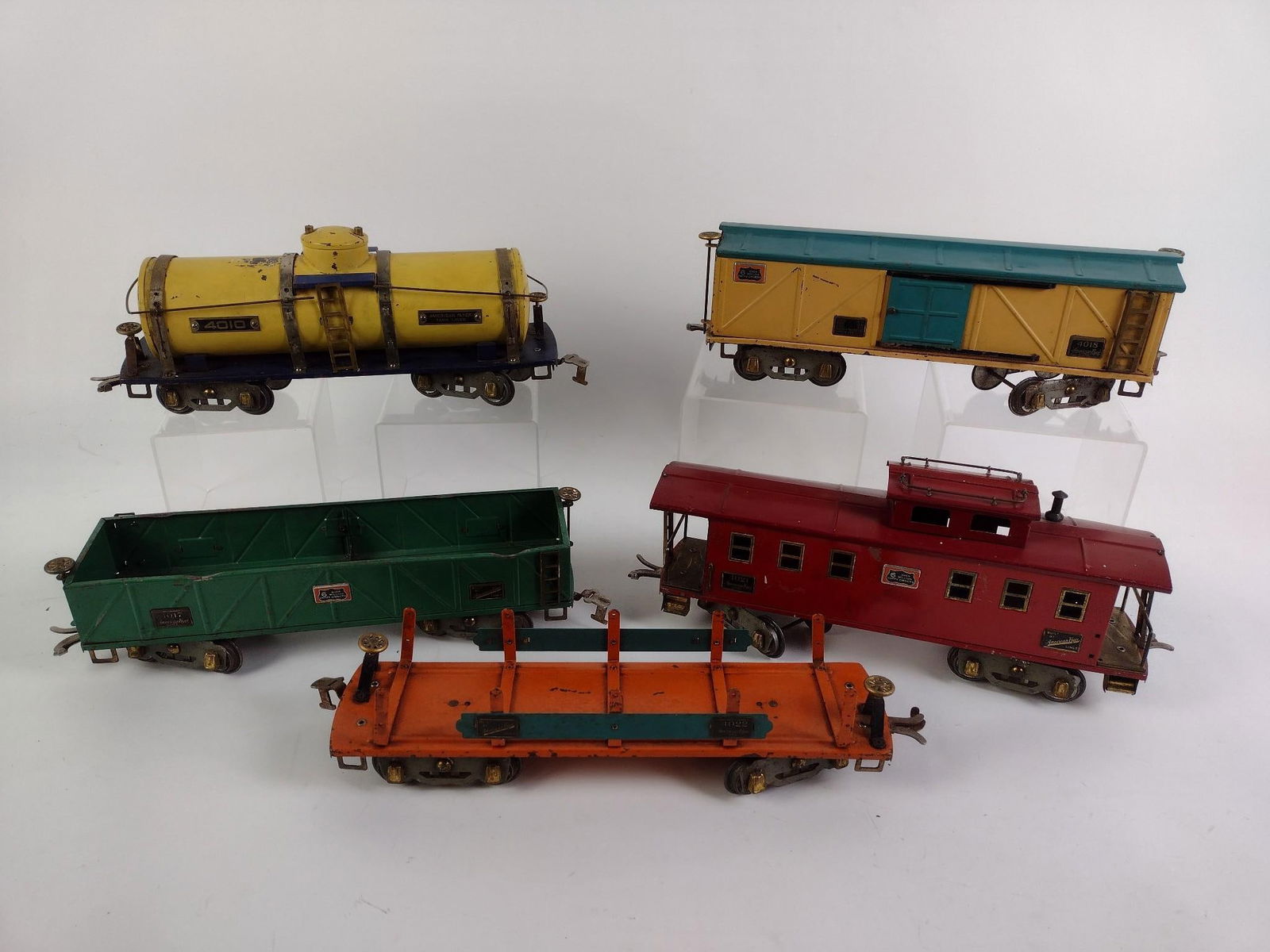 5 Pcs of American Flyer Wide Gauge Freight Set: Includes Boxcar #4018, Tankcar #4010, Caboose #4021, Flatbed #4017, and Lumber Car #4022. CONDITION: Overall paint chipping, but appears good overall. Yellow tank car has loose metal pieces. MEASUREME