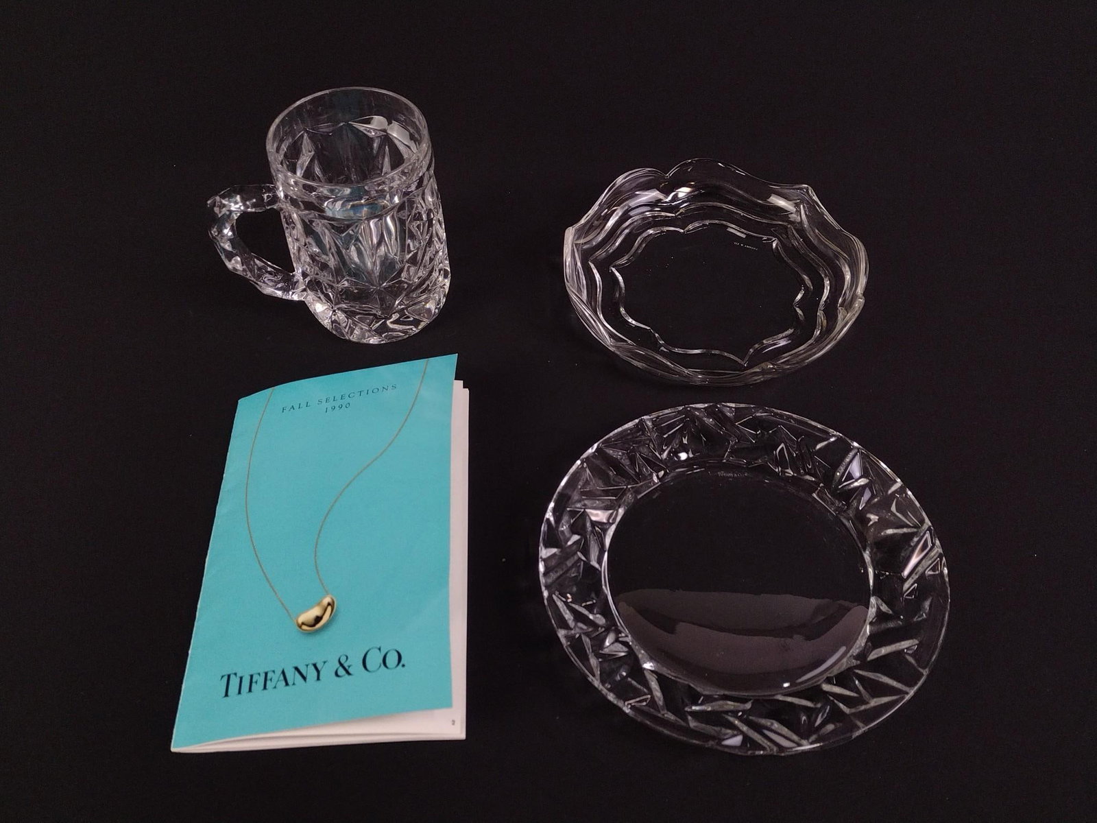 3 Pcs Tiffany & Co Glass: Includes mug and two plates. All marked Tiffany & Co. Also includes Tiffany pamphlet. 3-1/2" to 7-1/4" wide x 1-1/4" to 5" high.