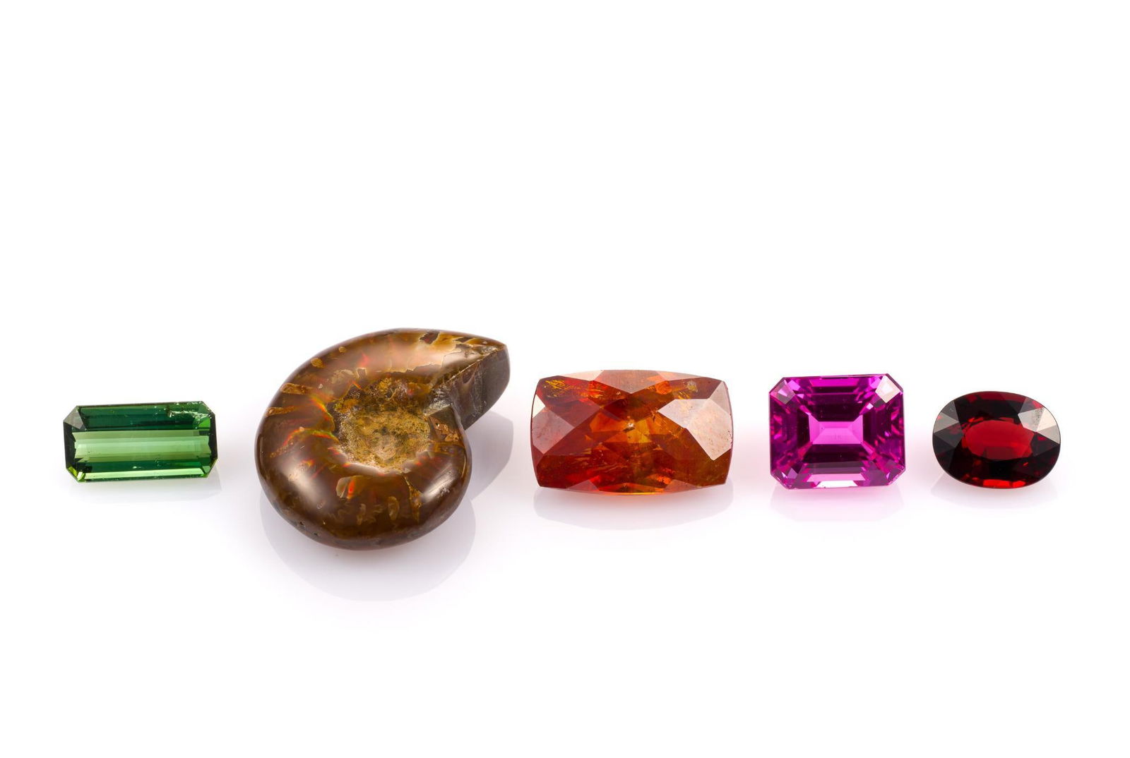 5 Unmounted Gemstones: Includes (1) Spessartite Garnet, cushion cut, 27.3 carats, I1-I2, natural; (2) Ammonite, rough, 55.02 carats, translucent, natural; (3) Tourmaline, emerald cut, 7.4 carats, VS2, no treatment; (4) Topa