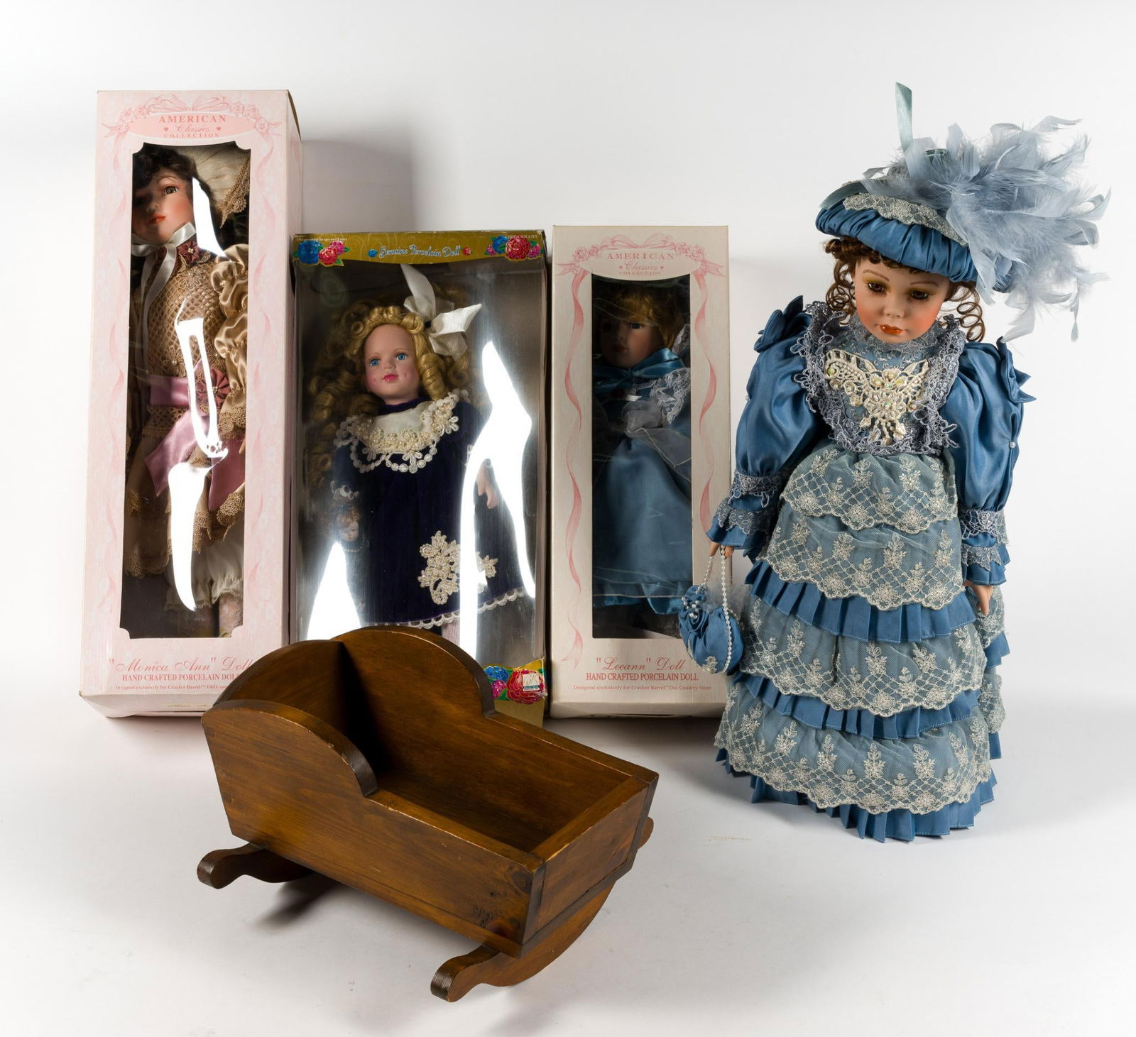 4 Dolls & Wood Toy Cradle: Dolls include American Classics and Camellia Gardens porcelain. Cradle 12-3/4" wide x 15" long x 8-1/4" high.