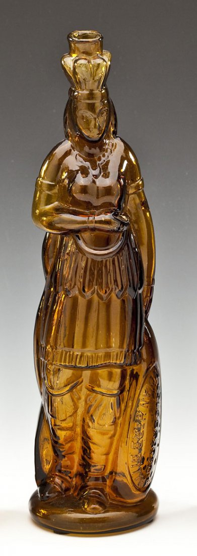 Brown's Amber Glass Indian Bitters Bottle: DESCRIPTION: Brown's amber glass Indian Queen herb bitters figural bottle. Rough lip and smooth base, embossed lettering on lower oval reserve marked, "Brown's Celebrated Indian Herb Bitters." The rea
