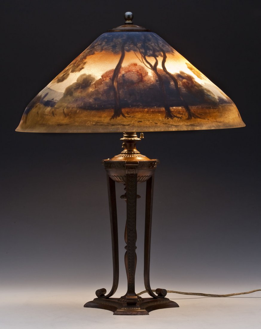 Pairpoint Company Reverse Glass Painted Table Lamp: DESCRIPTION: Pairpoint Company table lamp with a reverse glass painted shade of a landscape scene with figures. Patinated metal urn form trifed base. Three sockets, one with pull chain. Marked "Pairpo