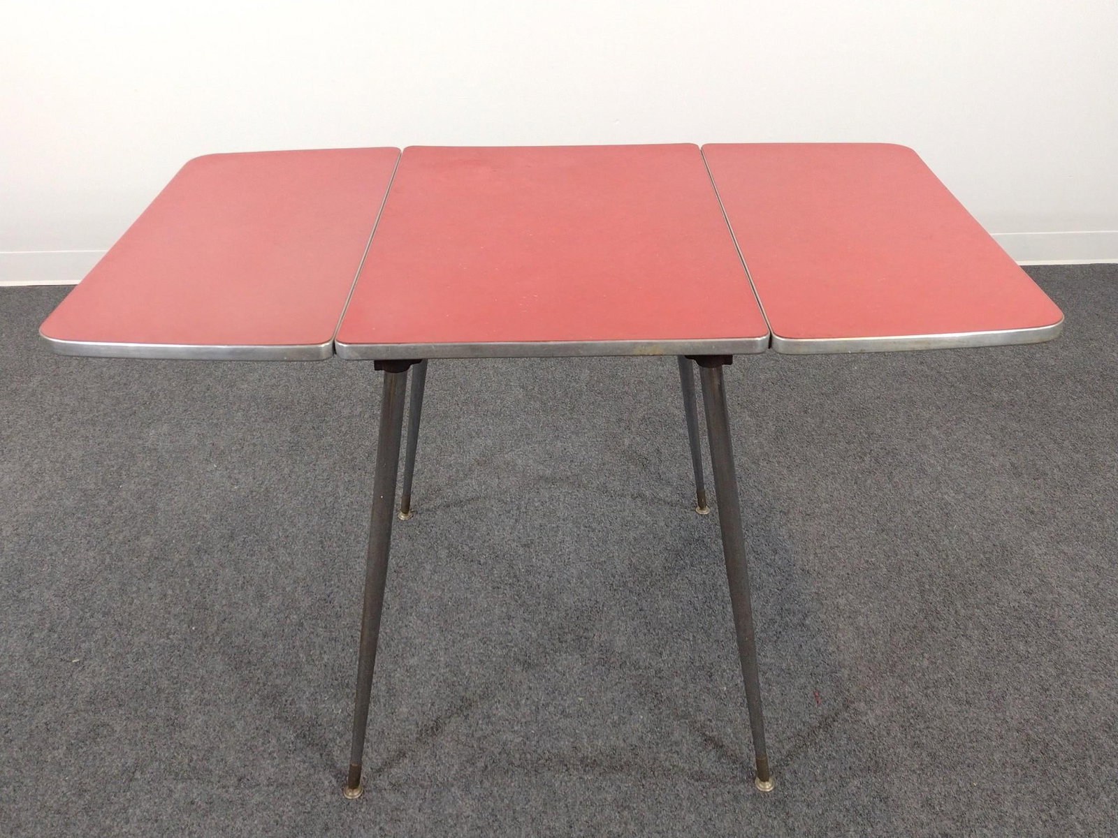 Red MCM Formica Table W/ Chrome Legs: Open 48", closed 20" wide X 30" deep X 29-1/2" high. Top has some finish loss. Legs have some scratches and rust.