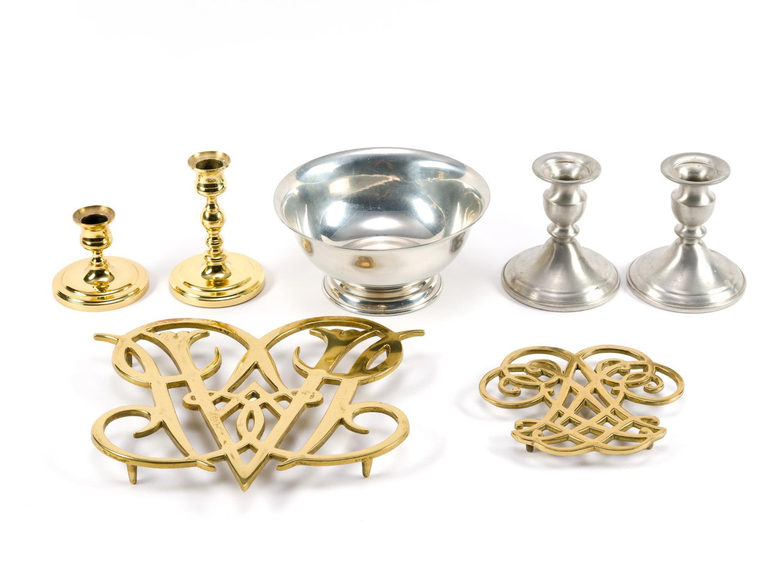 7 Pieces of Pewter & Brass: Includes 2 brass trivets, 1 pair of brass Baldwin candlesticks, 1 pair of pewter candle sticks and a pewter bowl. Largest trivet measures 9" x 9 - 1/2".
