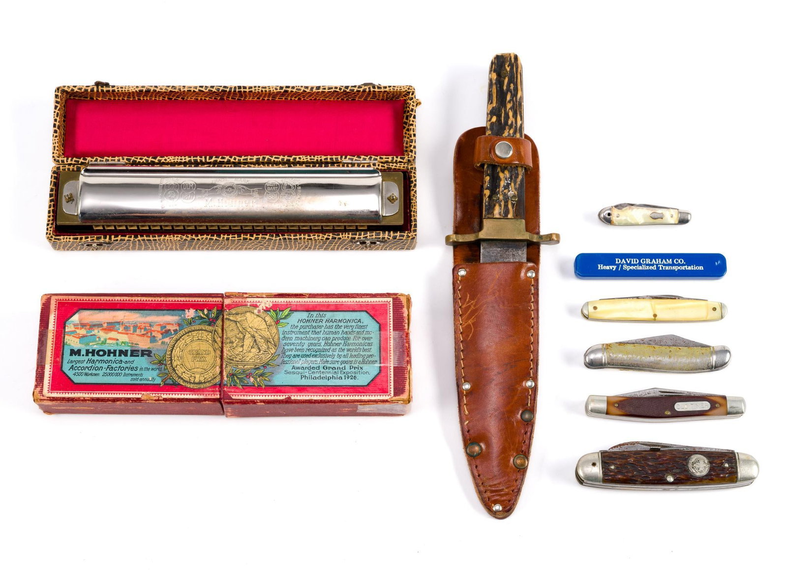 7 Pocket Knives & 2 Vintage Hohner Harmonicas: 6 folding knives and one straight knife with a sheath and buck handle. Straight knife is 9 - 7/8" long, Larger harmonica box measures 7 - 3/4" x 1 - 1/4" x 2 - 1/4".