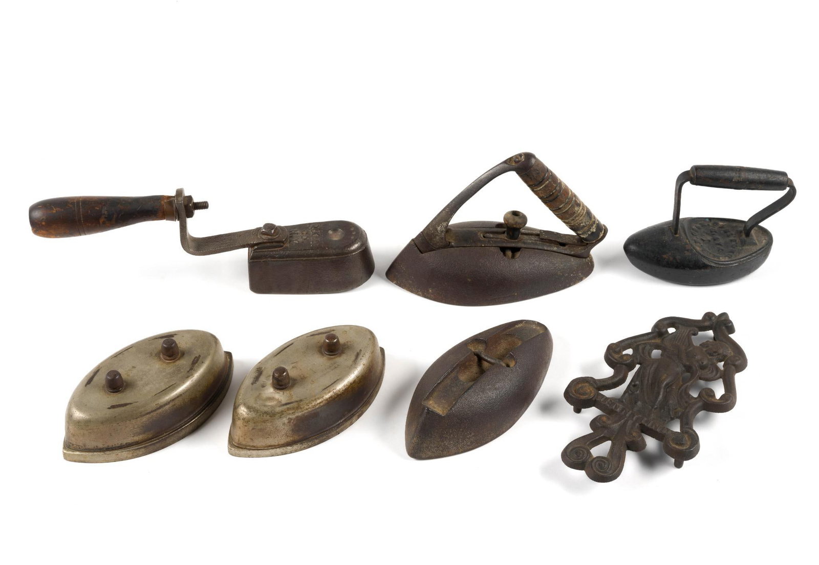 (Reconstruction Era) 6 Vintage Flatirons & Cast Iron Trivet: From a private collection. Trivet is dated 1945 and measures 8 - 3/4" x 4 - 3/4" x 1/2" and the smallest iron measures 5 - 1/4" x 2 - 3/4" x 4 - 1/2". Largest iron measures 8" x 3 - 1/2" x 5 - 1/2".