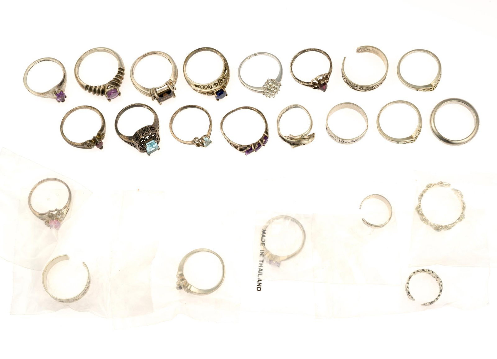 23 Sterling Silver Rings: Seven are unopened in the original package. At least one, the simple band with half-round cross section is unmarked. The weight of the rings not including the unmarked band is 2.2 troy ounces. Most of