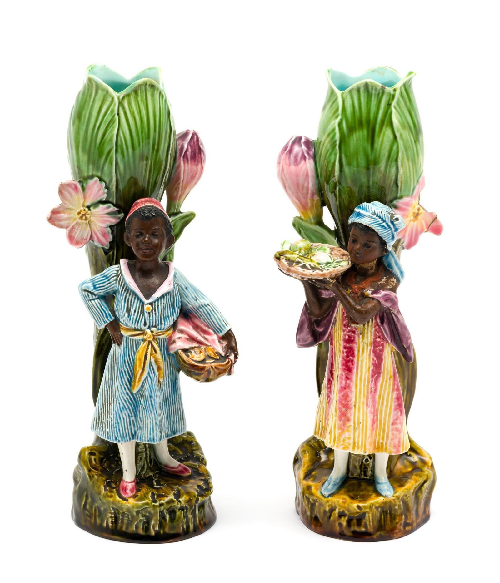 Pair of 19th C Barbotine Majolica Vases: Pair of late 19th-century French barbotine majolica figural vases depicting African children standing before tulip-form vase holders, each carrying baskets of fruit. Modeled with polychrome glazes on 