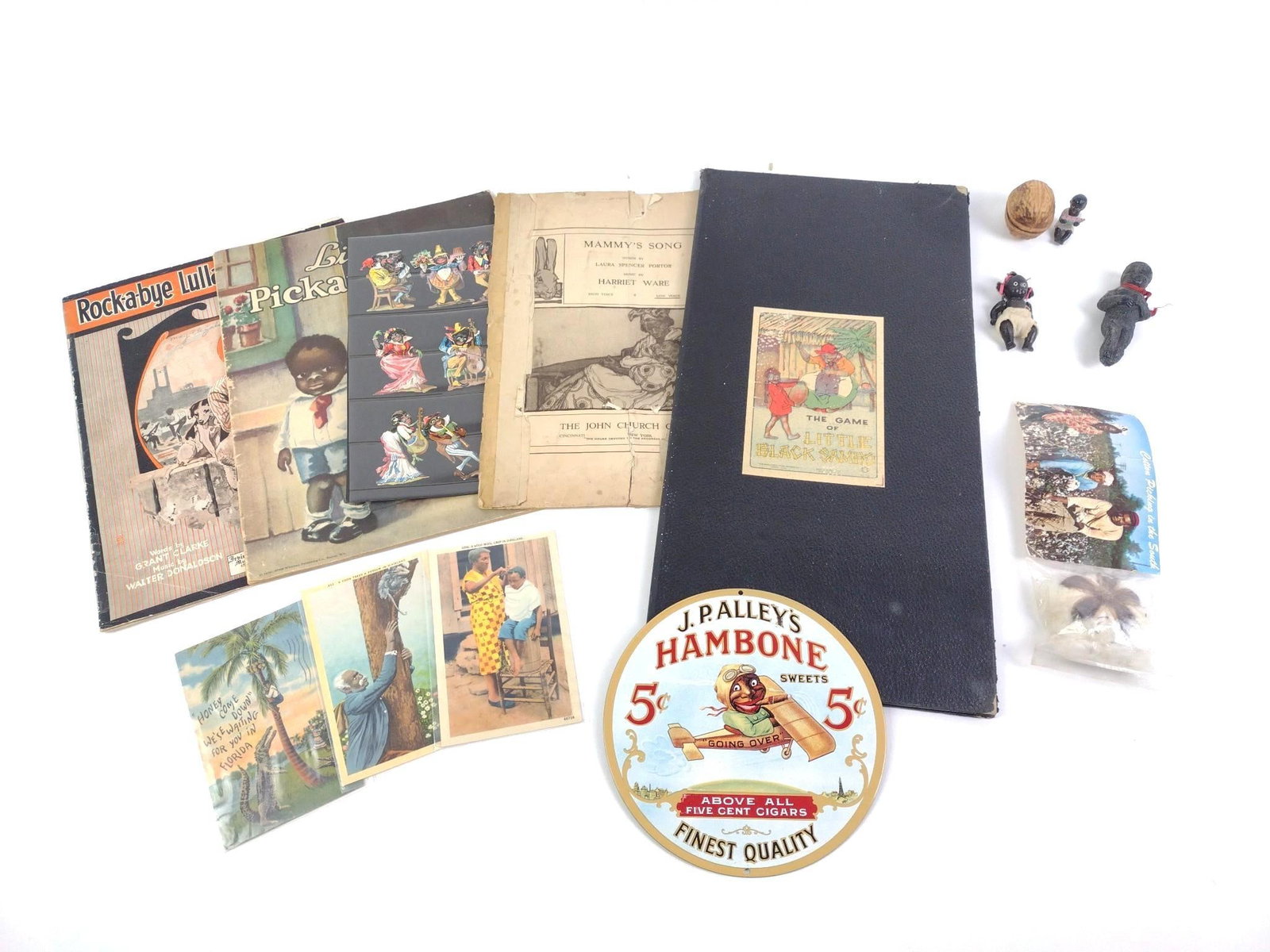 Black Americana Incl. Postcards: Also includes "The Game of Little Black Sambo" game board, a J.P. Alley's Metal advertisement, a small metal figurine eating fruit in a walnut shaped trinket box, a baby figurine, song books,
